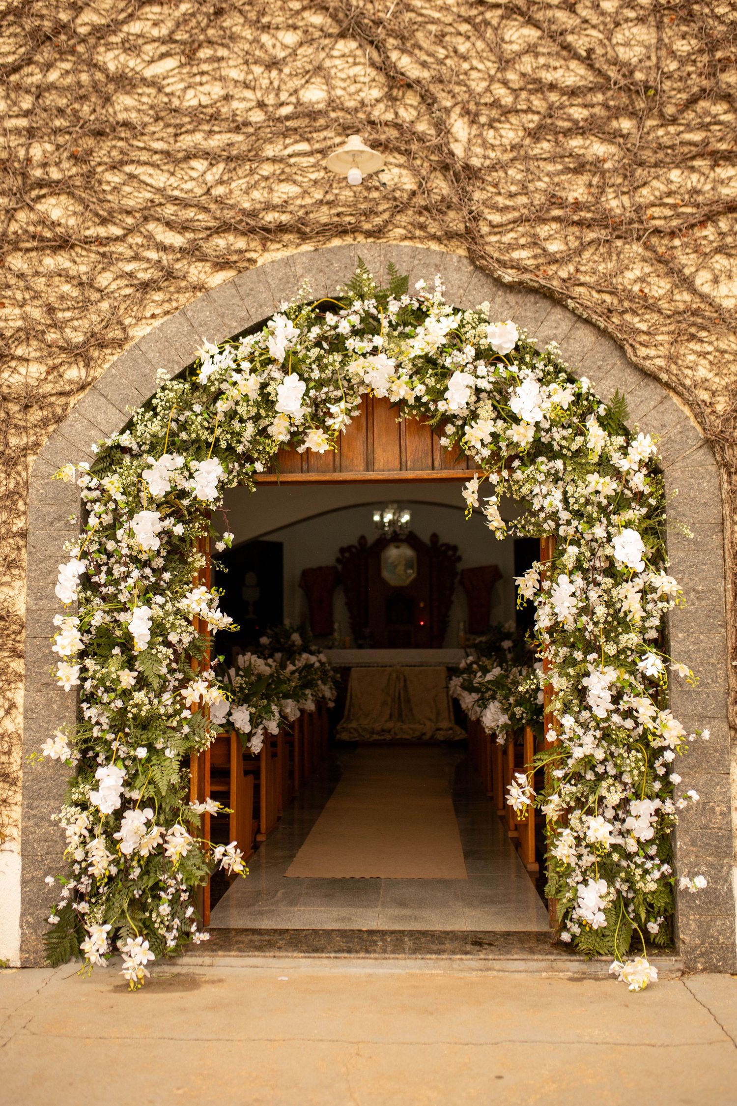 Elegant floral arch with white flowers and greenery framing a church entrance for a wedding ceremony.