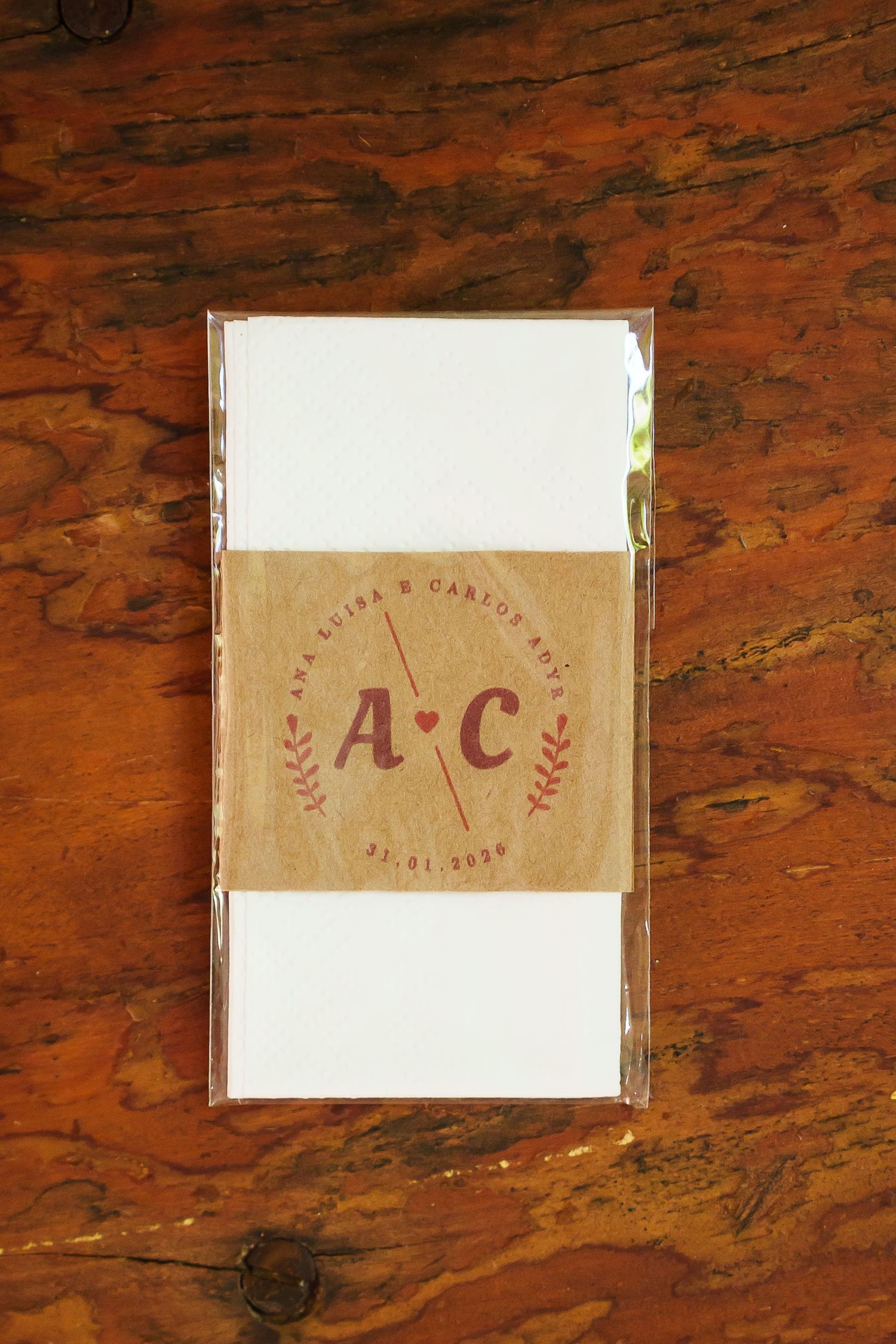 Custom kraft paper belly band with monogram A&C wedding stationery set on rustic wooden surface.