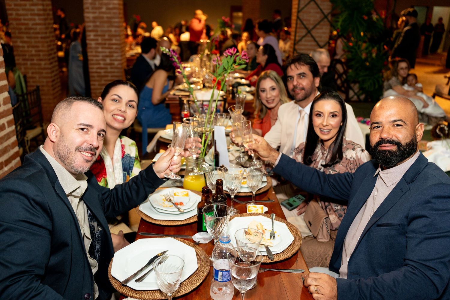 Group of friends toasting with wine glasses at a festive restaurant dinner party, dressed in elegant attire.