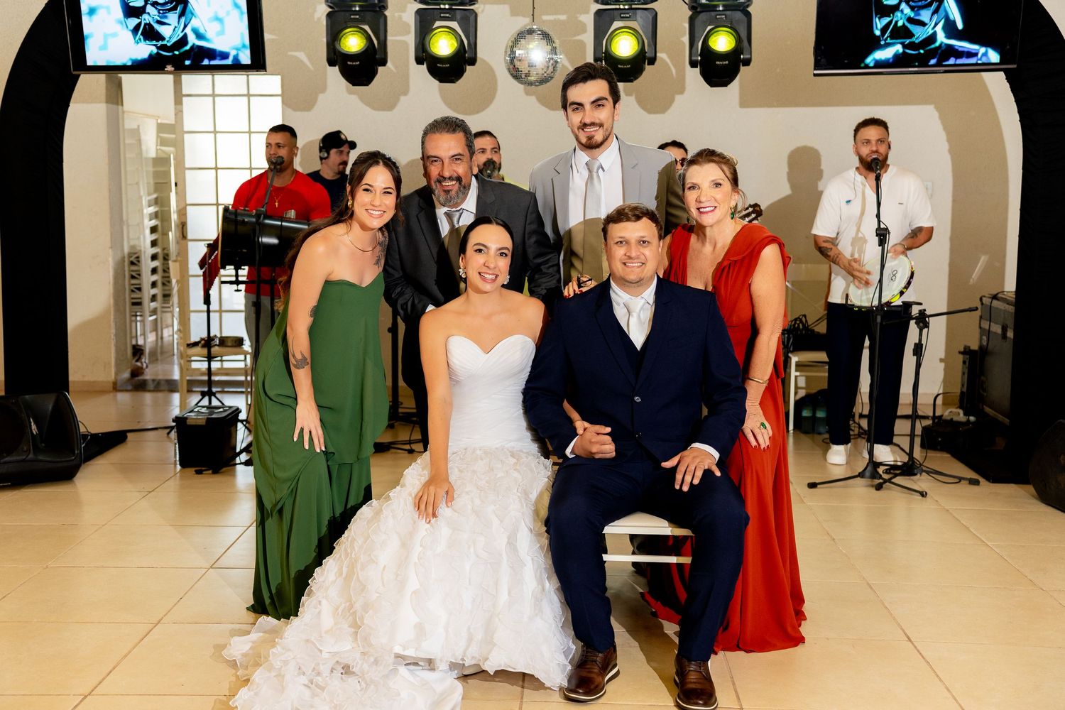 Wedding couple seated in front with family and friends posing together in an elegant reception venue.