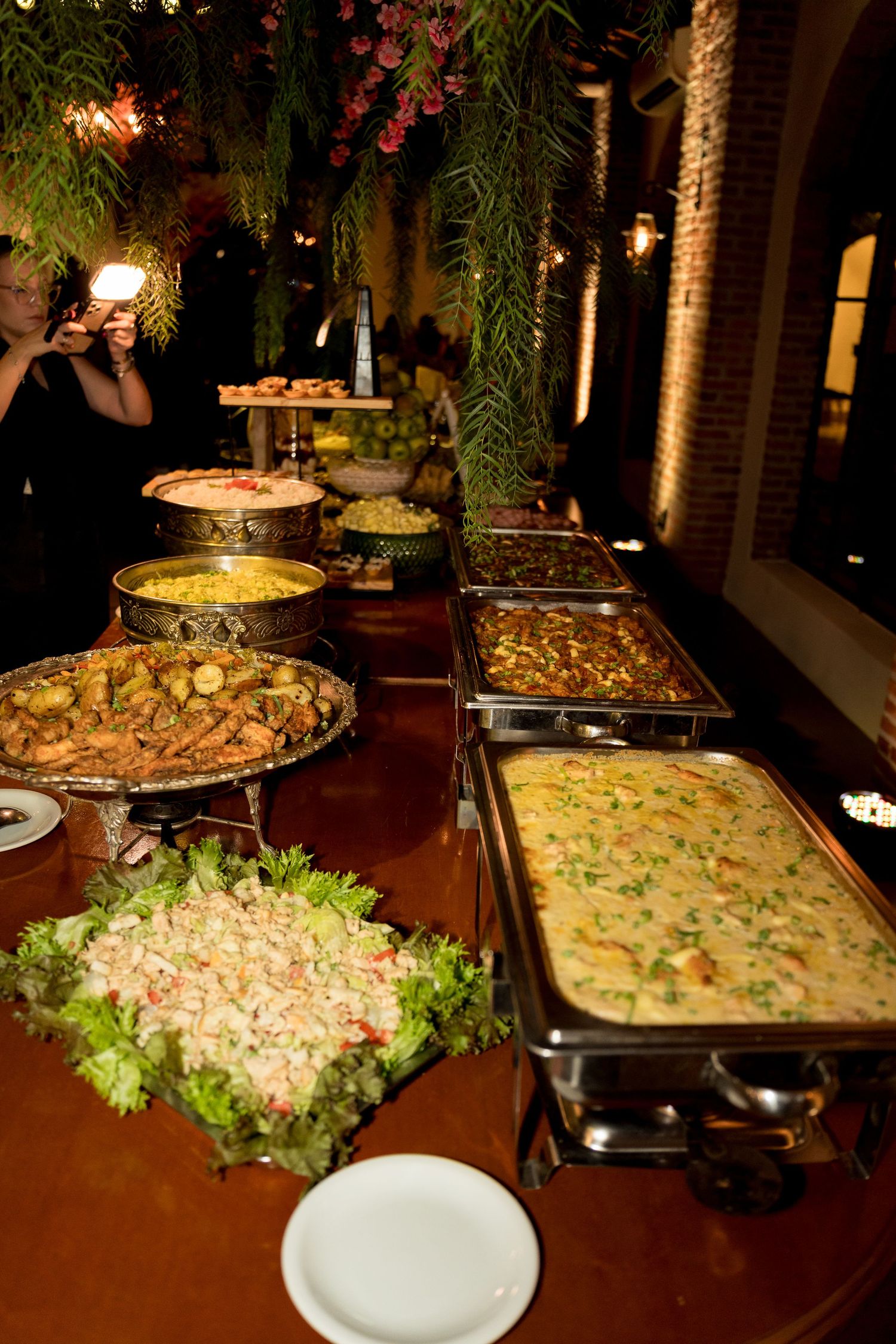 Elegant outdoor buffet spread with multiple chafing dishes filled with various hot dishes and salads at a catered event.