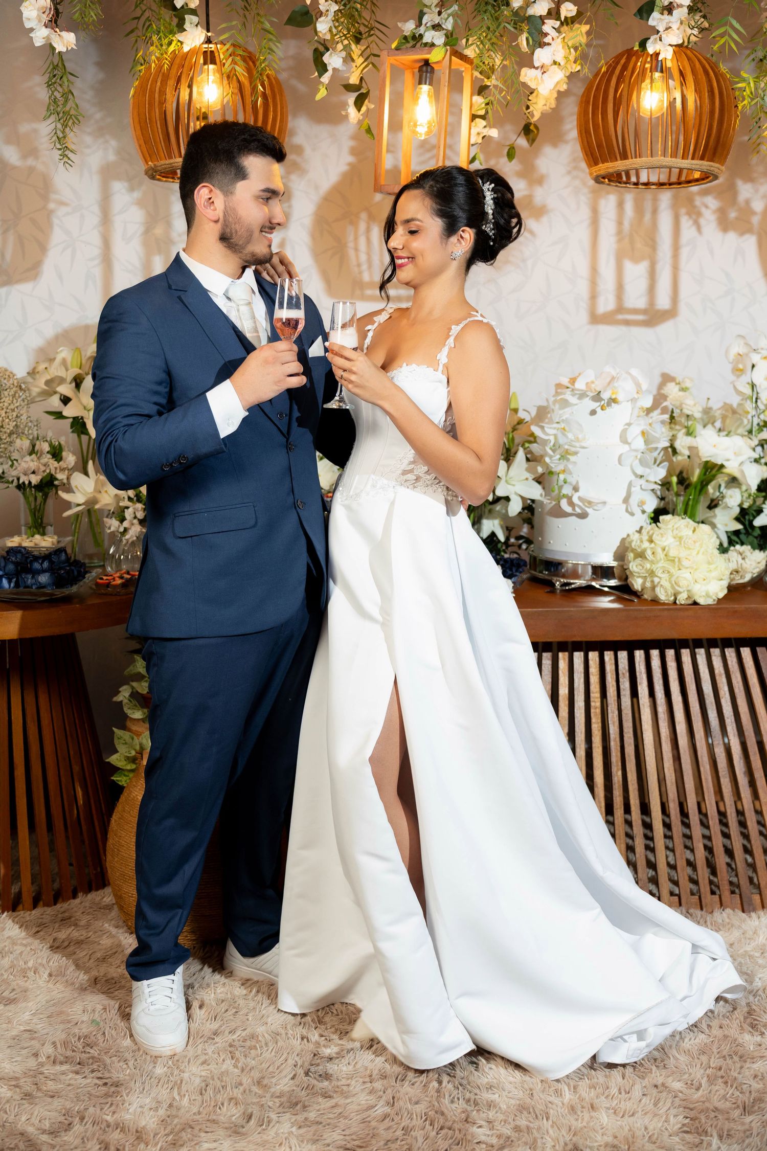 Bride and groom toasting with champagne glasses at wedding reception, decorated with flowers and warm lighting.