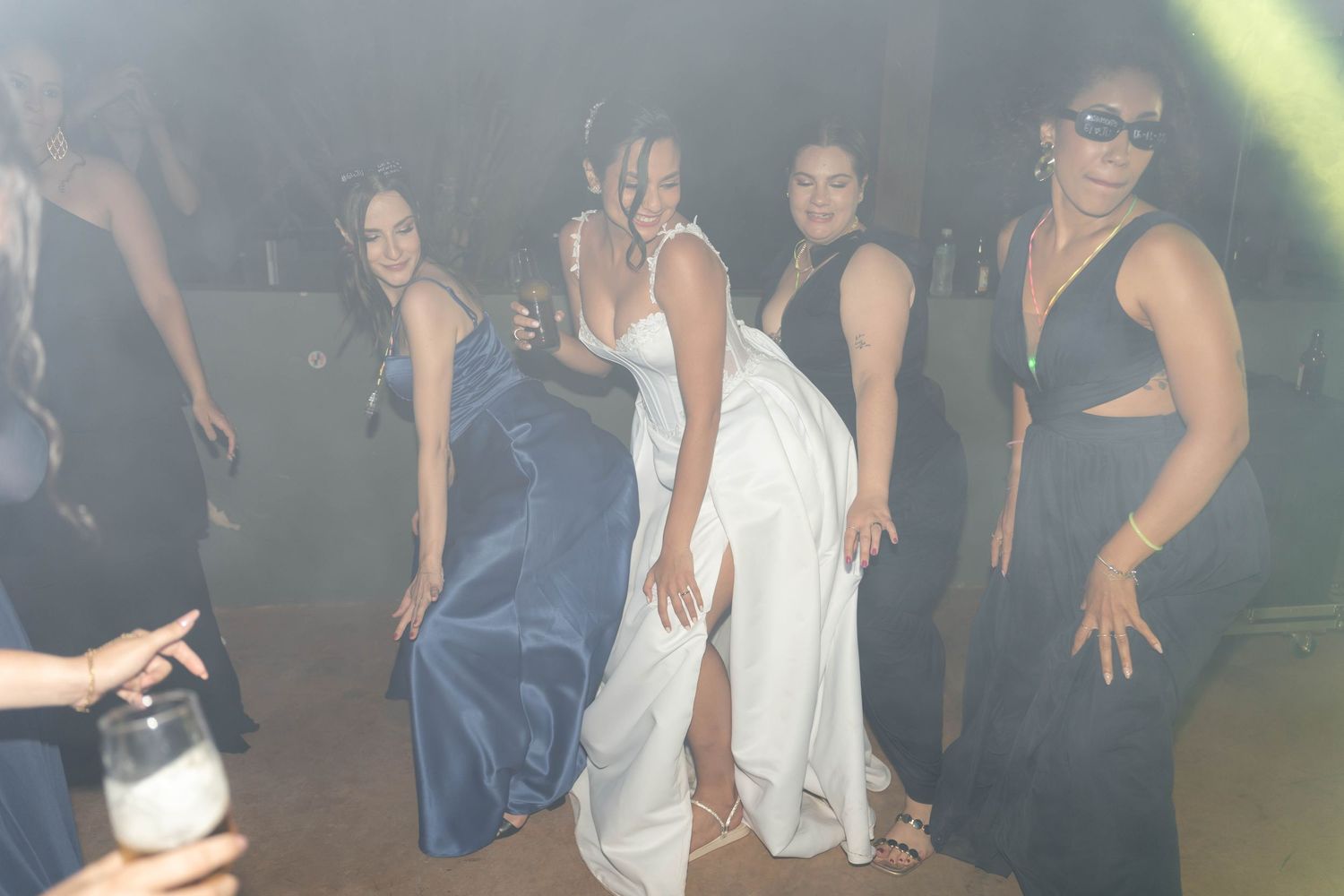 Women in formal gowns dancing together at an evening wedding reception celebration.