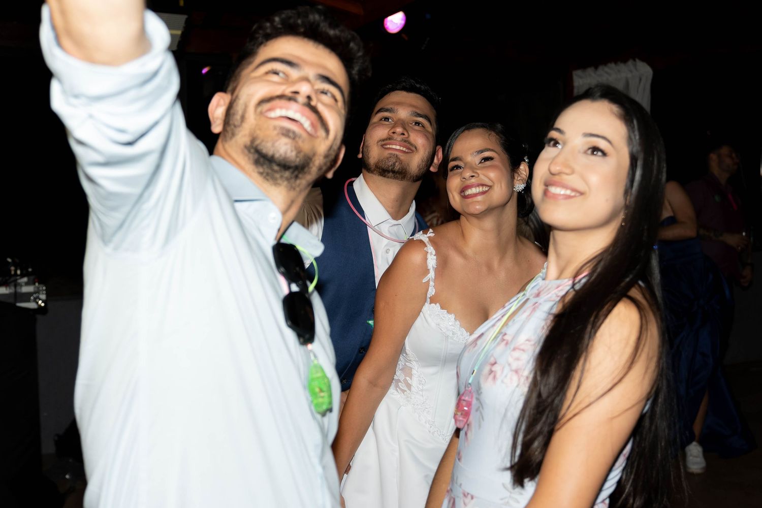 Four young adults smiling and taking a selfie together at a nighttime social event or party.