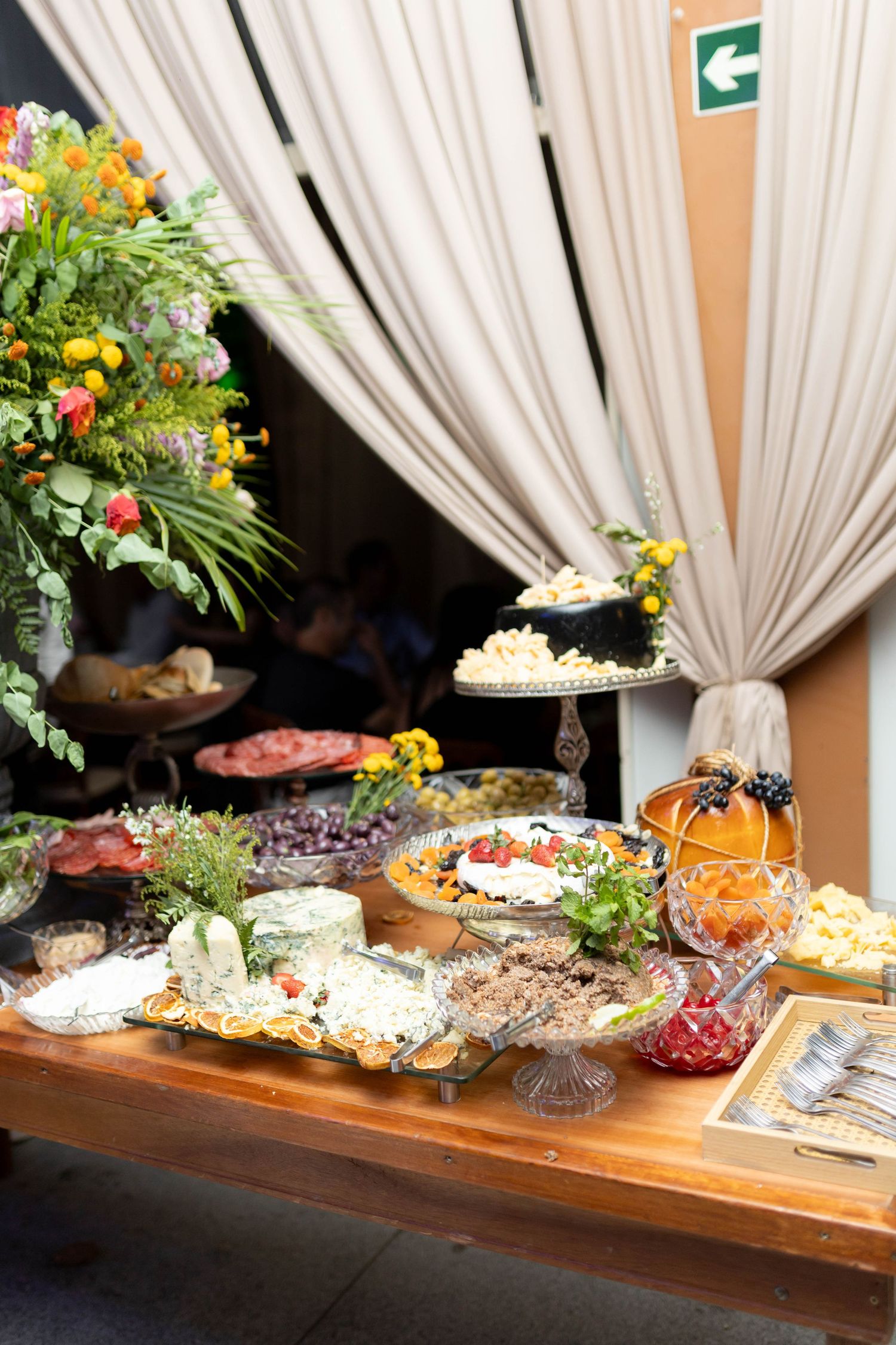 Elegant buffet table with assorted cheeses, salads, and appetizers adorned with fresh flowers at a catered event.
