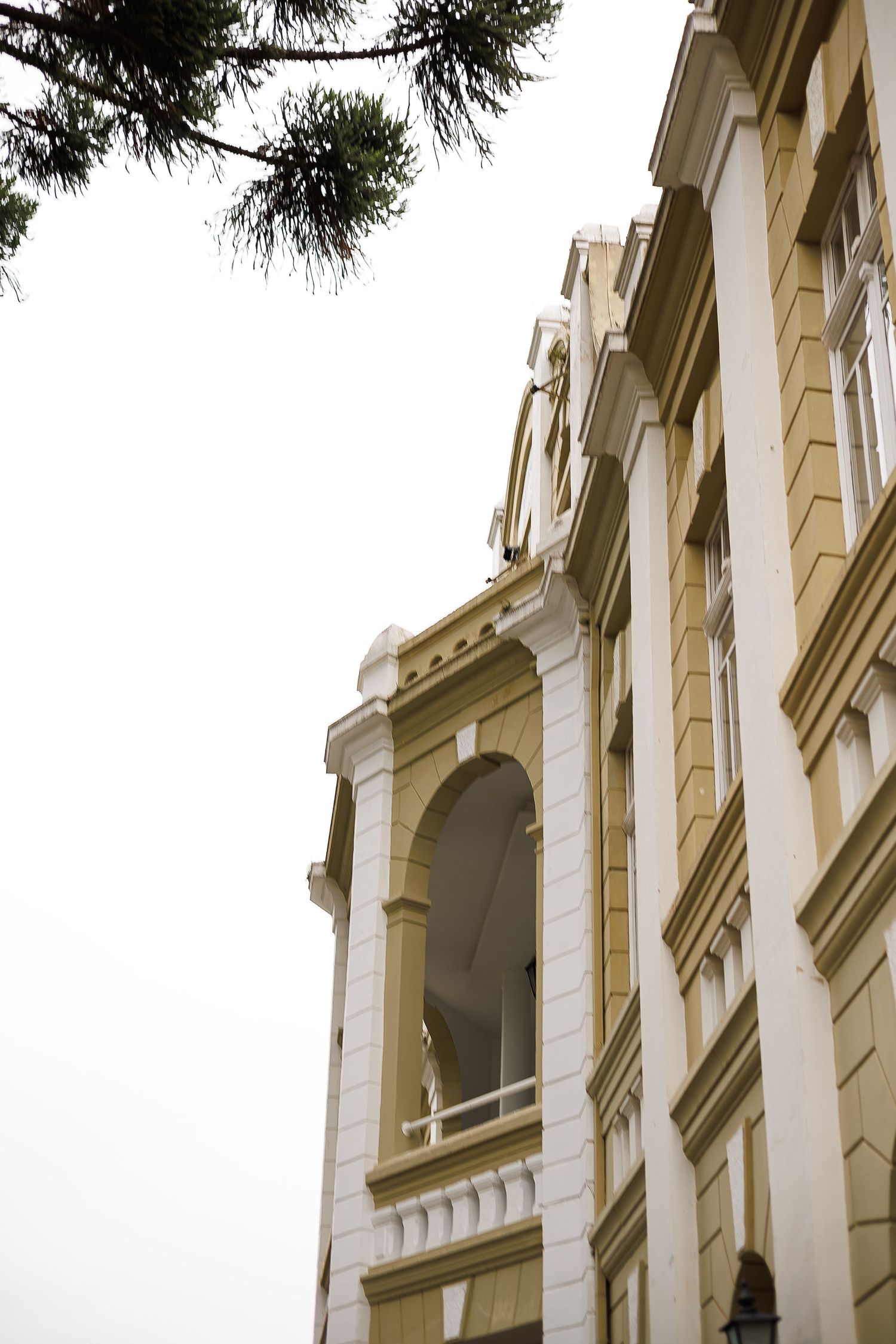 Historic building with ornate white and tan facade, arched windows, and classical architectural details against overcast sky.