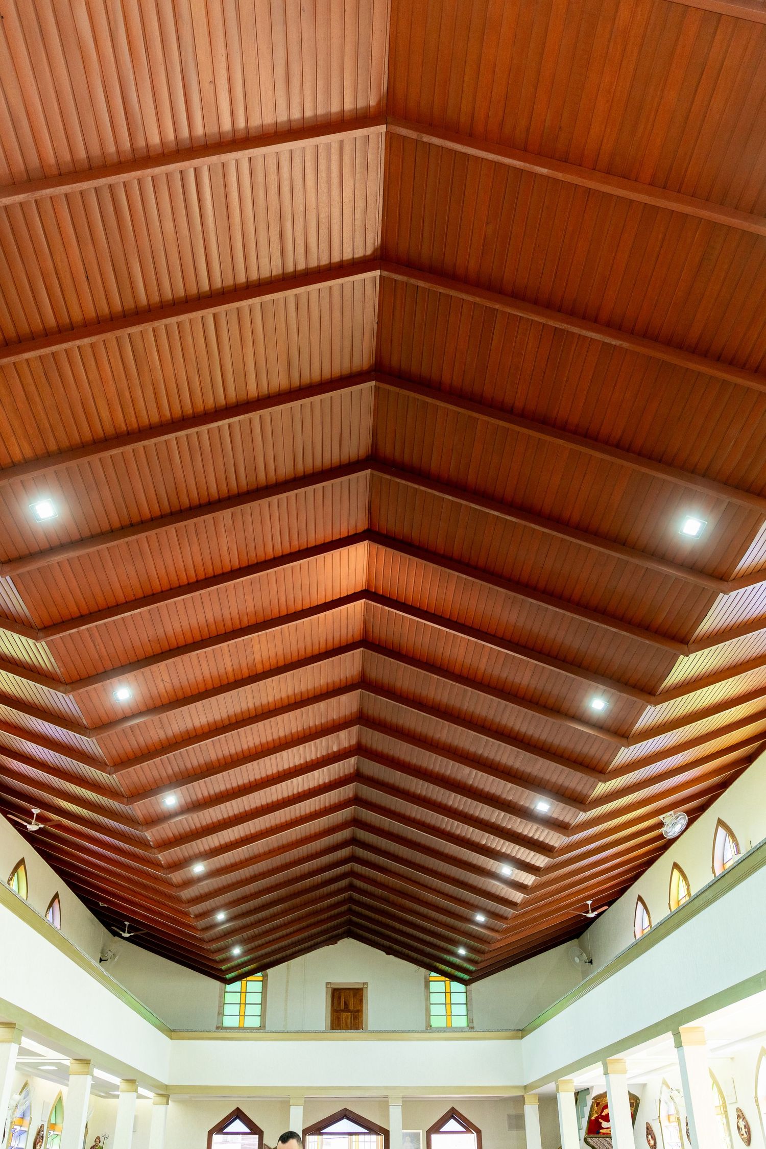 Elegant wooden cathedral ceiling with recessed lighting and vaulted beams in a spacious church interior.