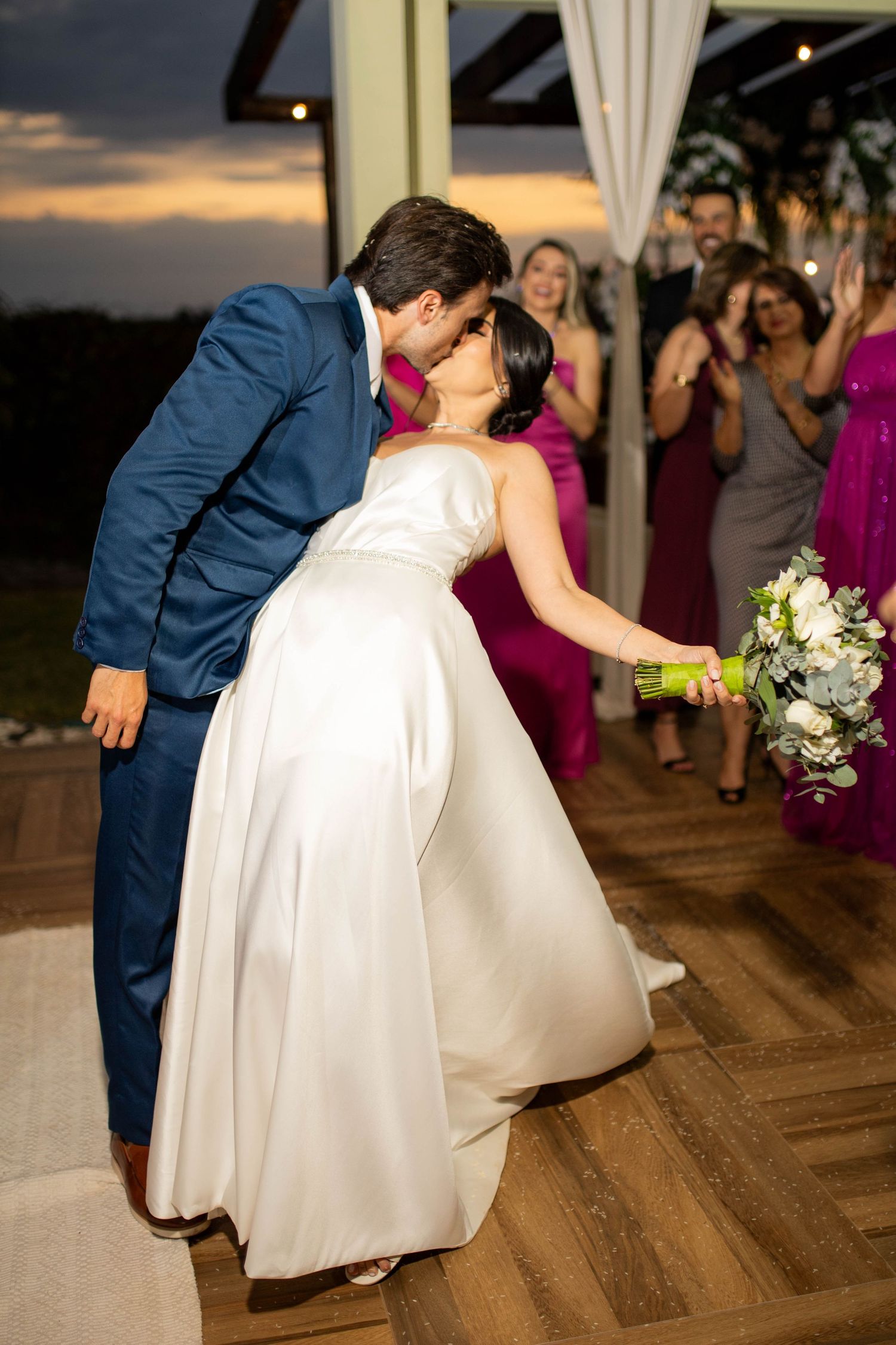 Bride and groom share a romantic kiss on the dance floor at their outdoor evening wedding reception.