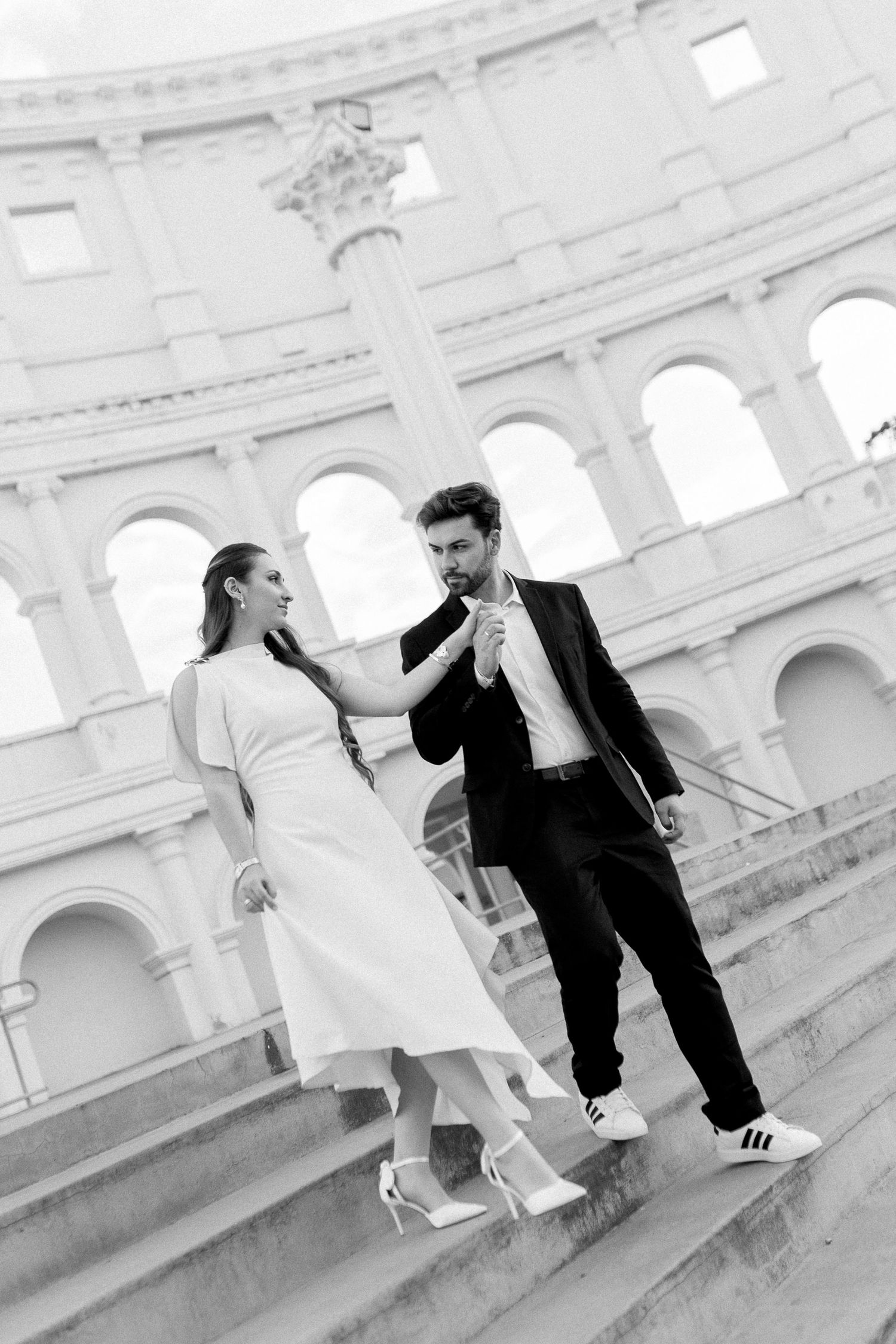 Black and white photo of a couple on steps in front of the Colosseum in Rome, Italy.