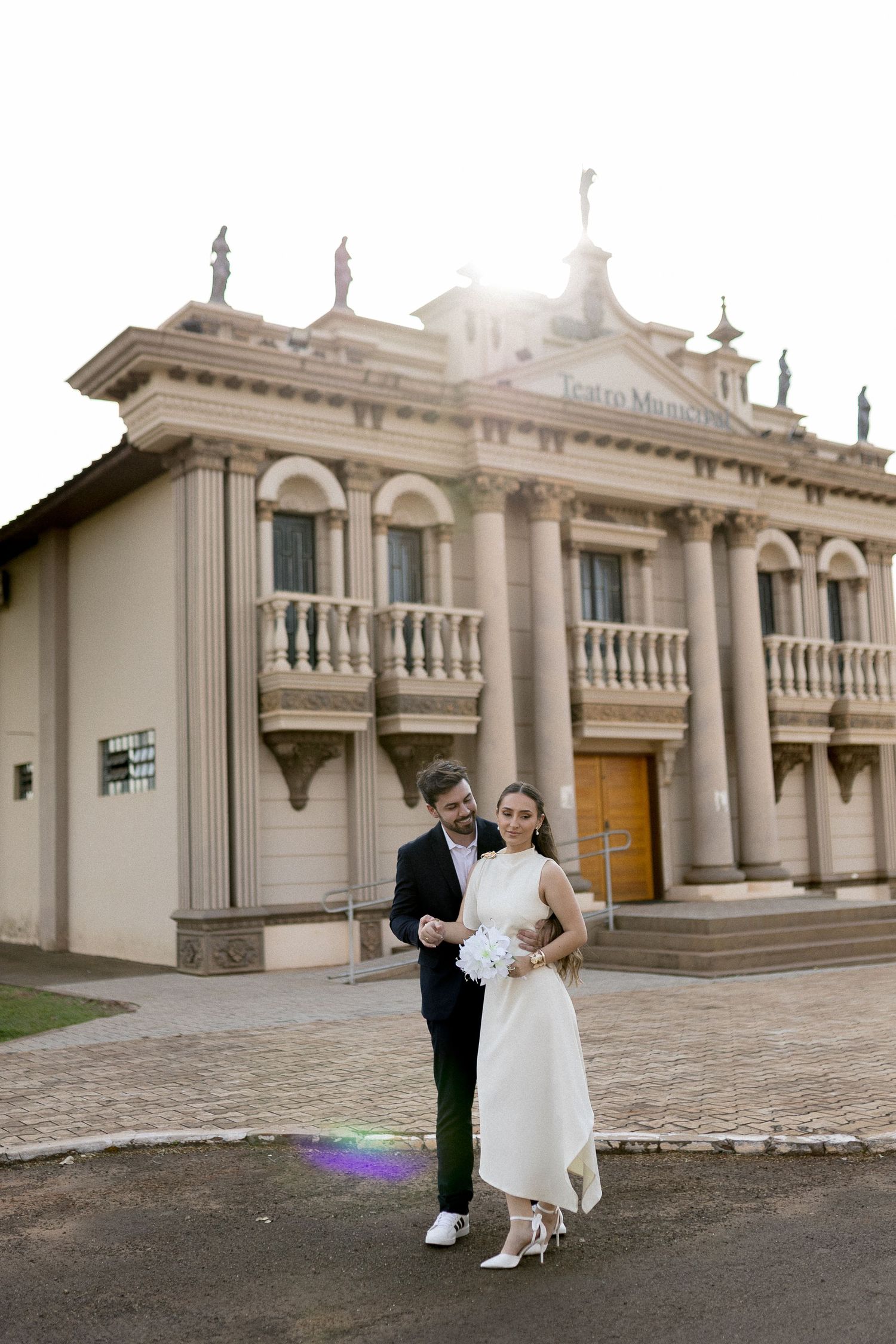 Bride and groom posing in front of an elegant neoclassical building on their wedding day.