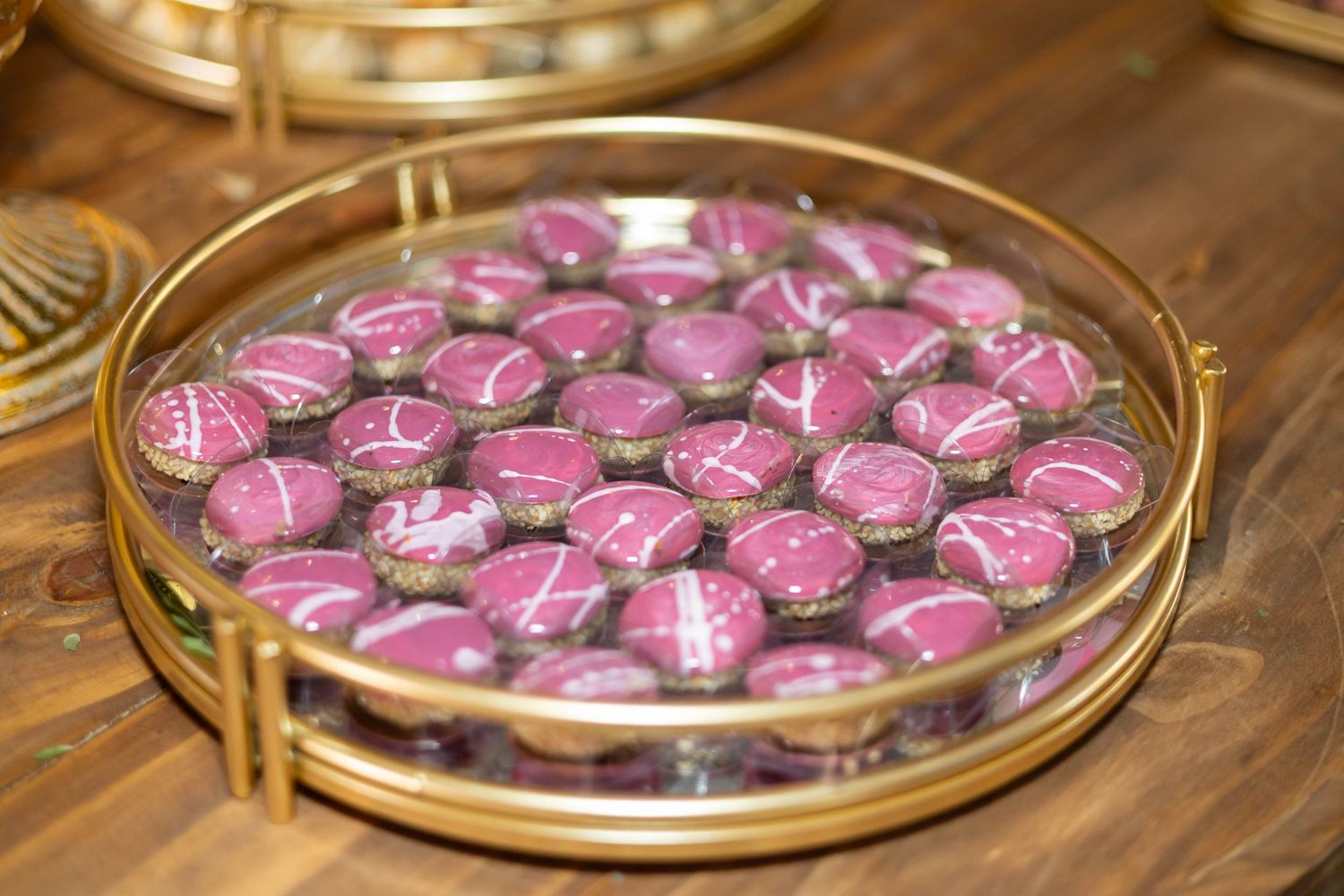 Gold tray with pink and brown decorated macarons arranged neatly, perfect for elegant dessert displays.