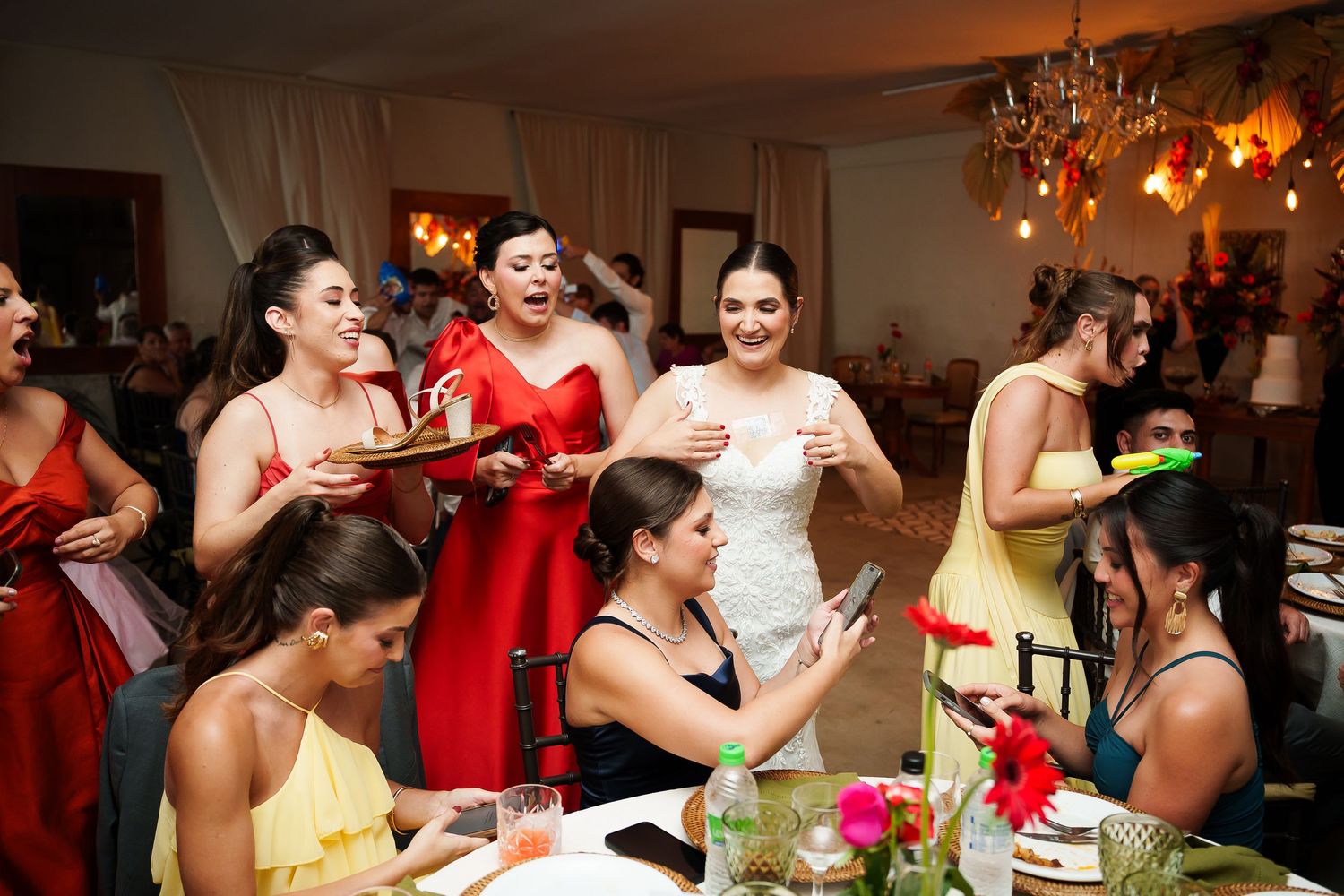 Bride in white dress celebrates with bridesmaids in colorful gowns at a festive wedding reception.