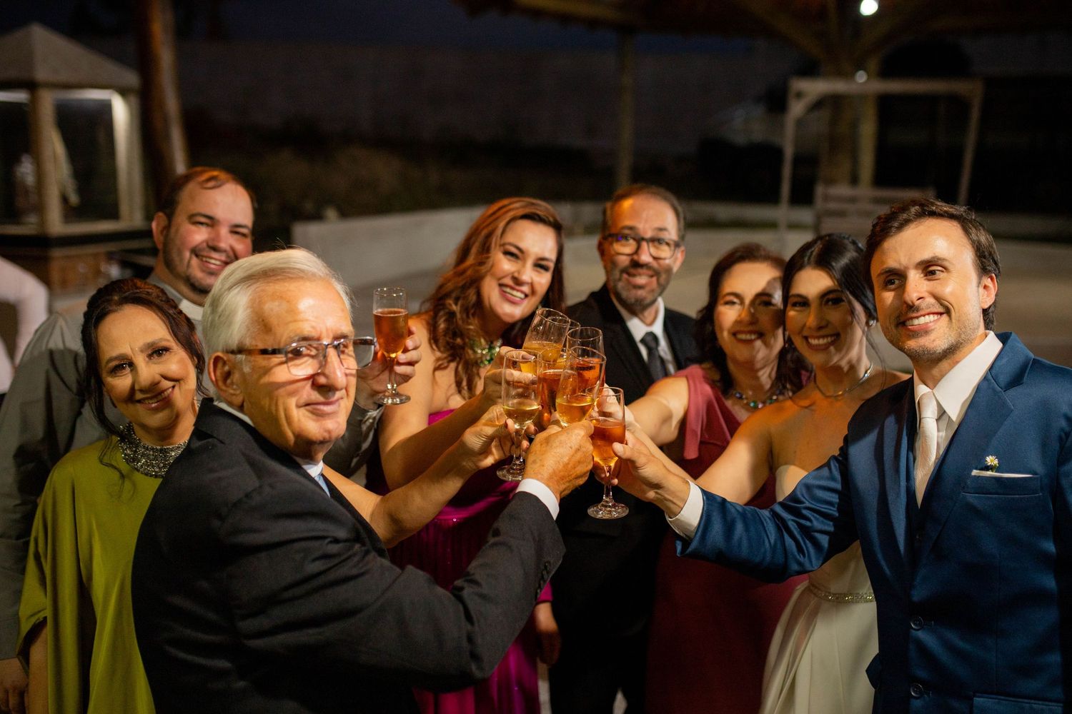 Wedding guests raising champagne glasses in a celebratory toast at an elegant evening reception.