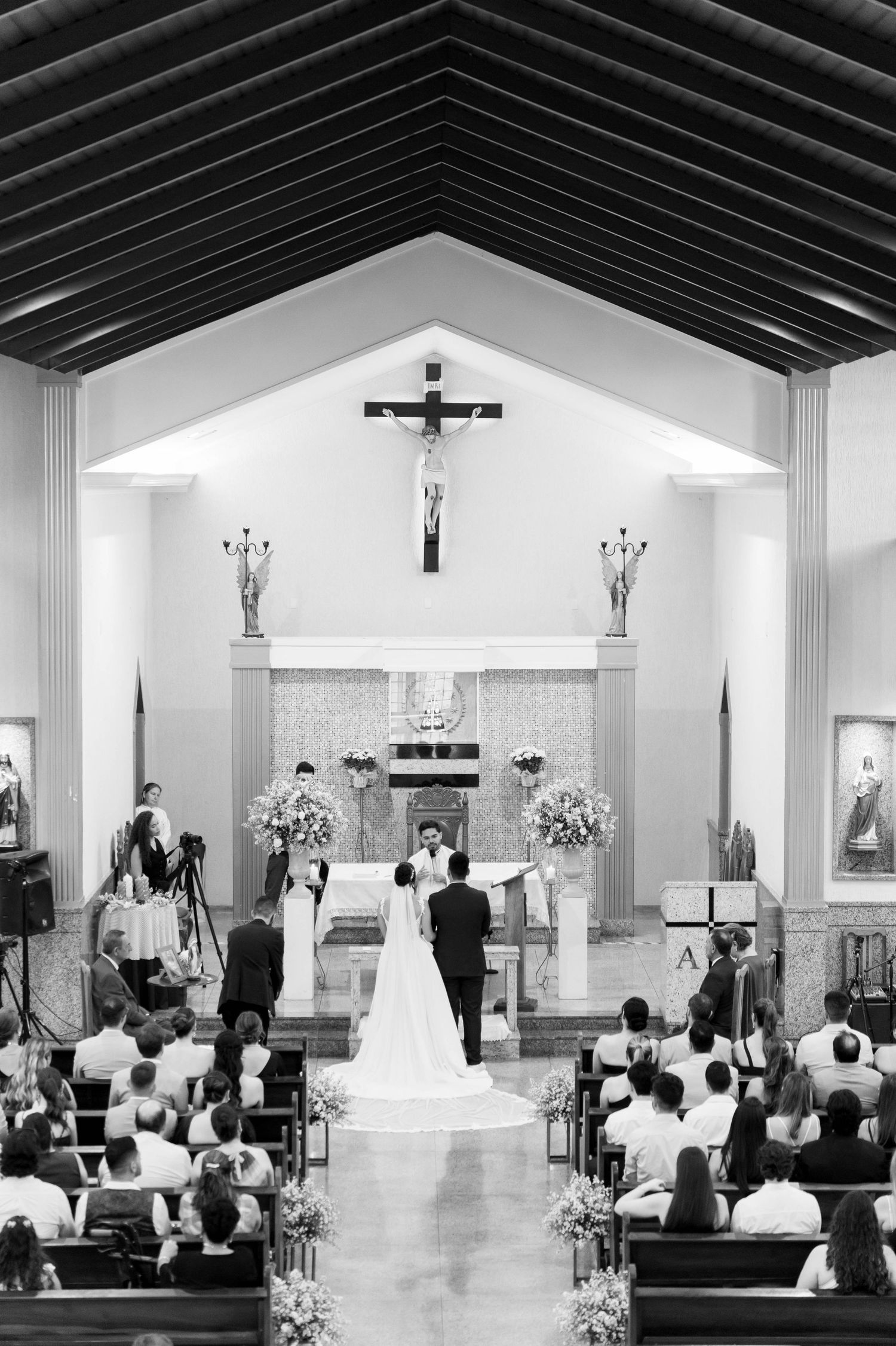 Black and white photo of a bride and groom at the altar of a Catholic church during their wedding ceremony.