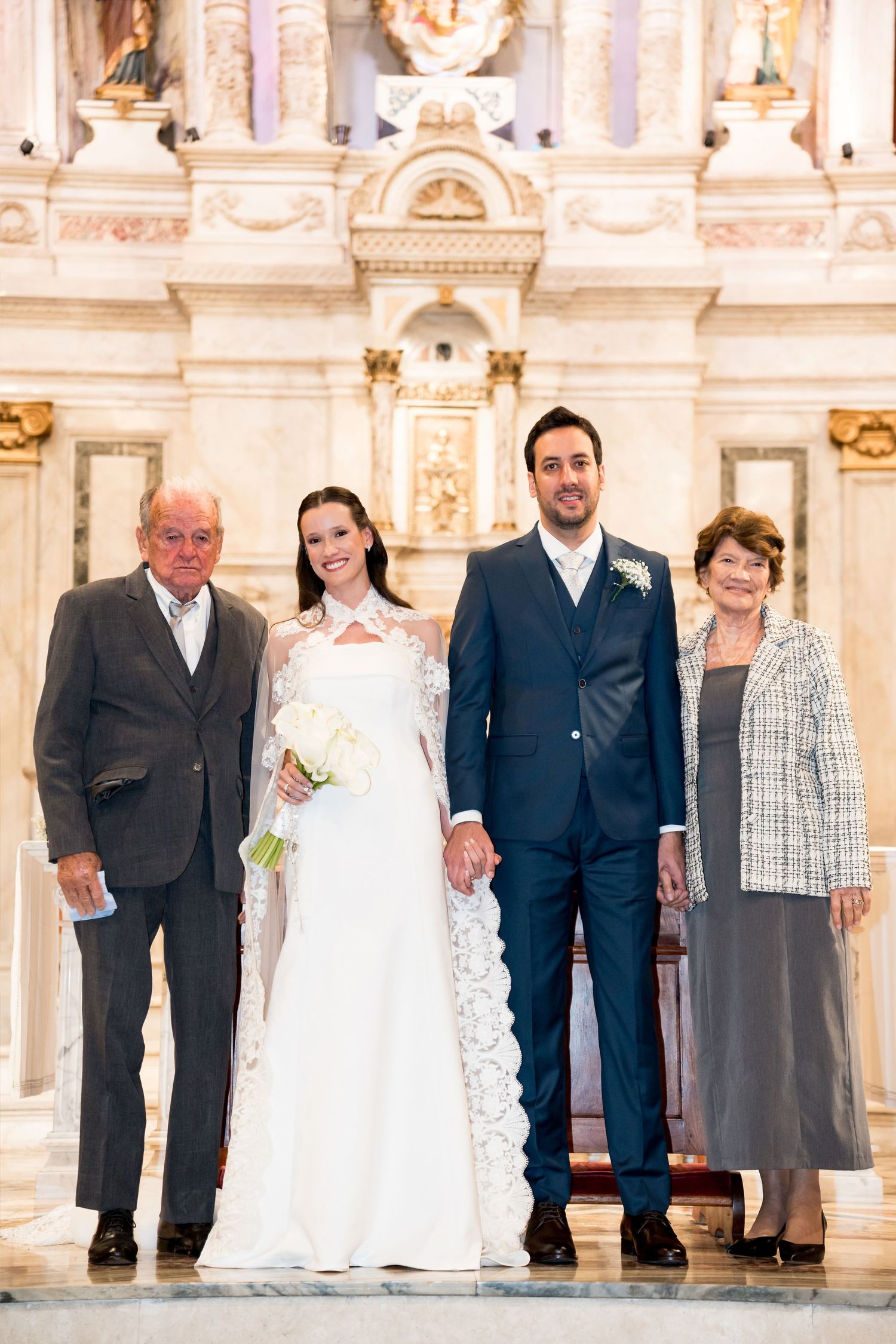 Bride and groom pose with family members at church altar on wedding day.