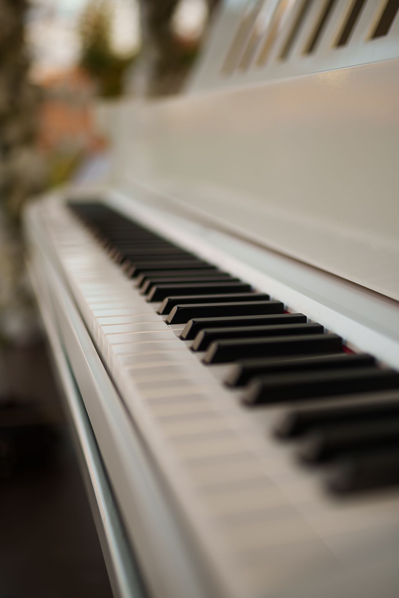 Close-up of a white piano keyboard with black and white keys in sharp focus, with a blurred background.