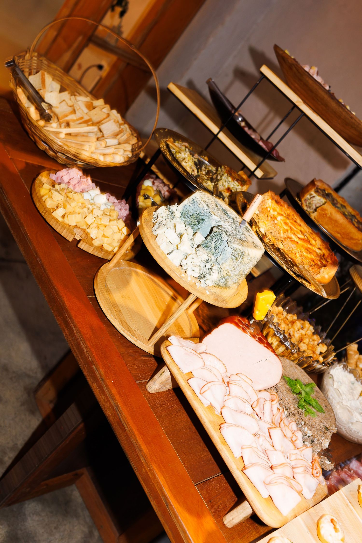 Rustic wooden table displaying an elegant charcuterie spread with aged cheeses, cured meats, and artisan breads.