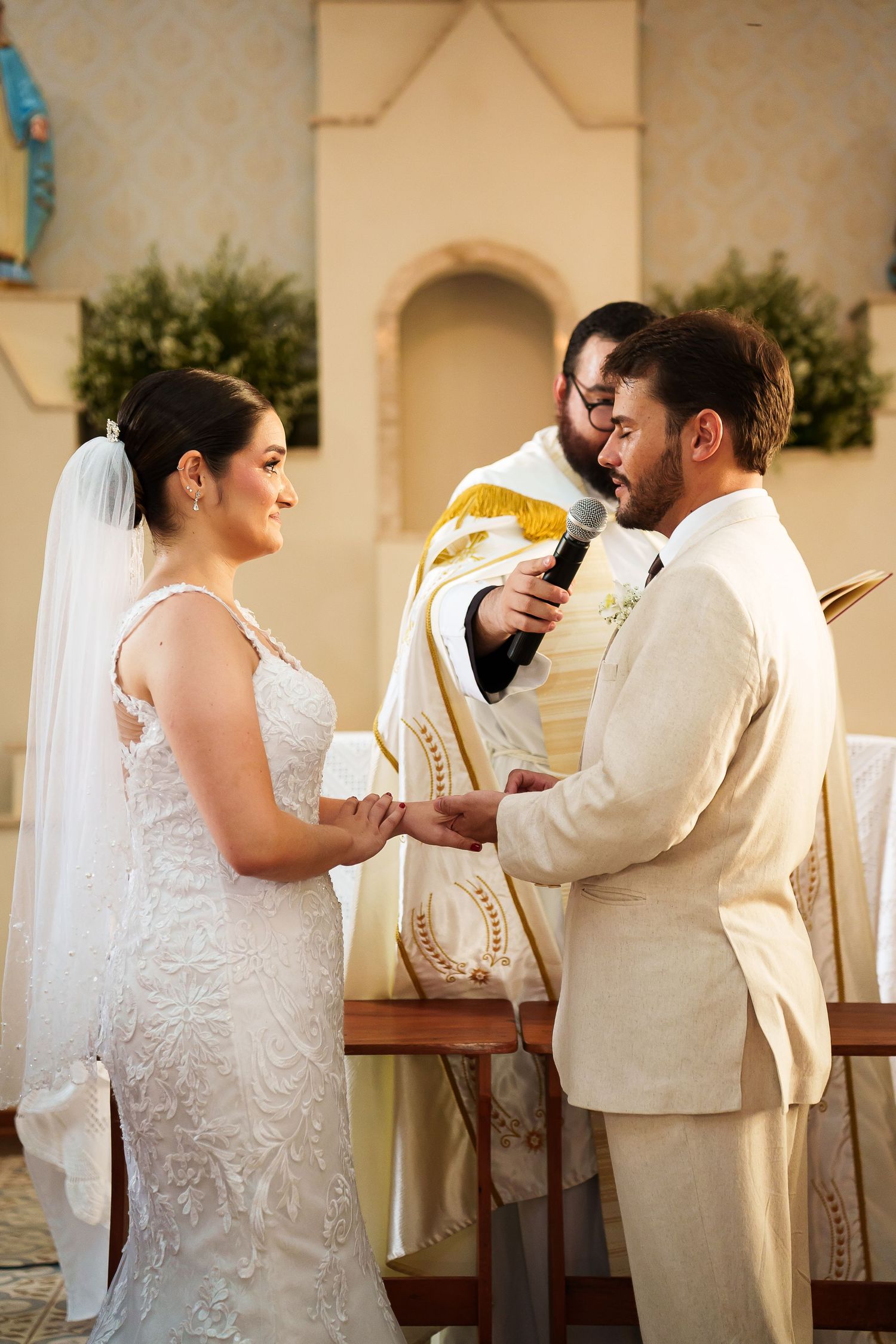 Bride and groom exchange vows at church altar with priest officiating wedding ceremony.
