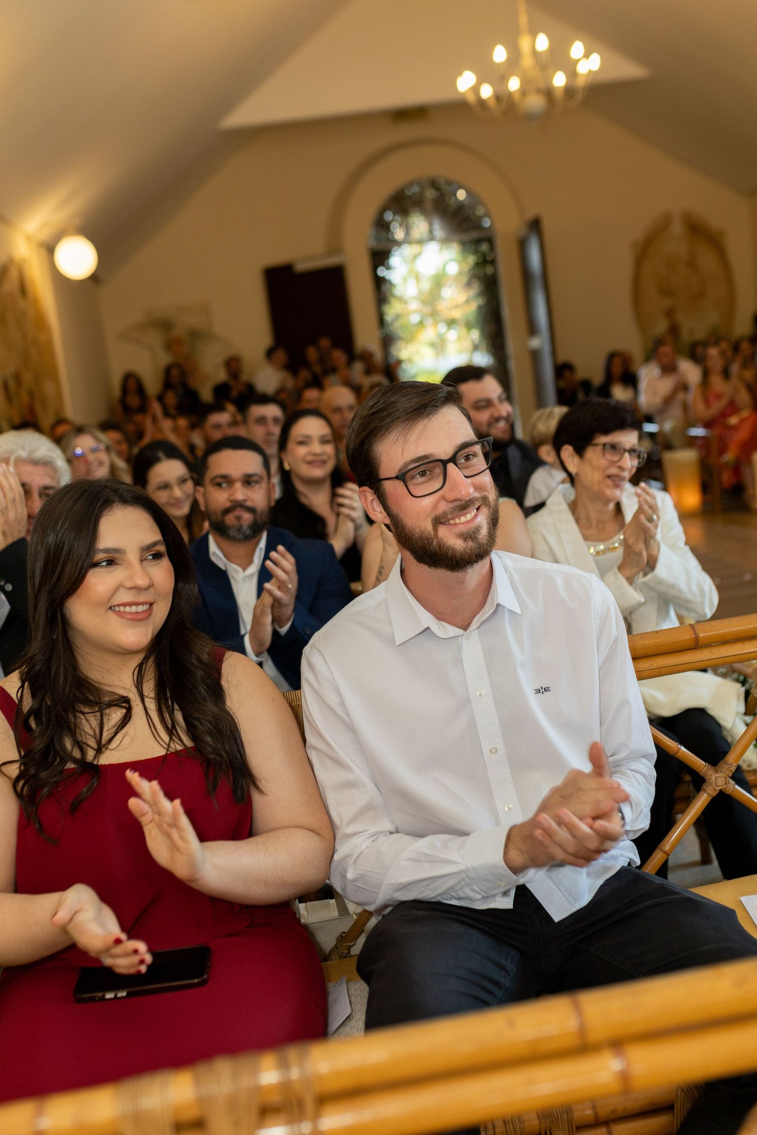 Guests clapping and smiling at a wedding ceremony inside an elegant chapel venue.