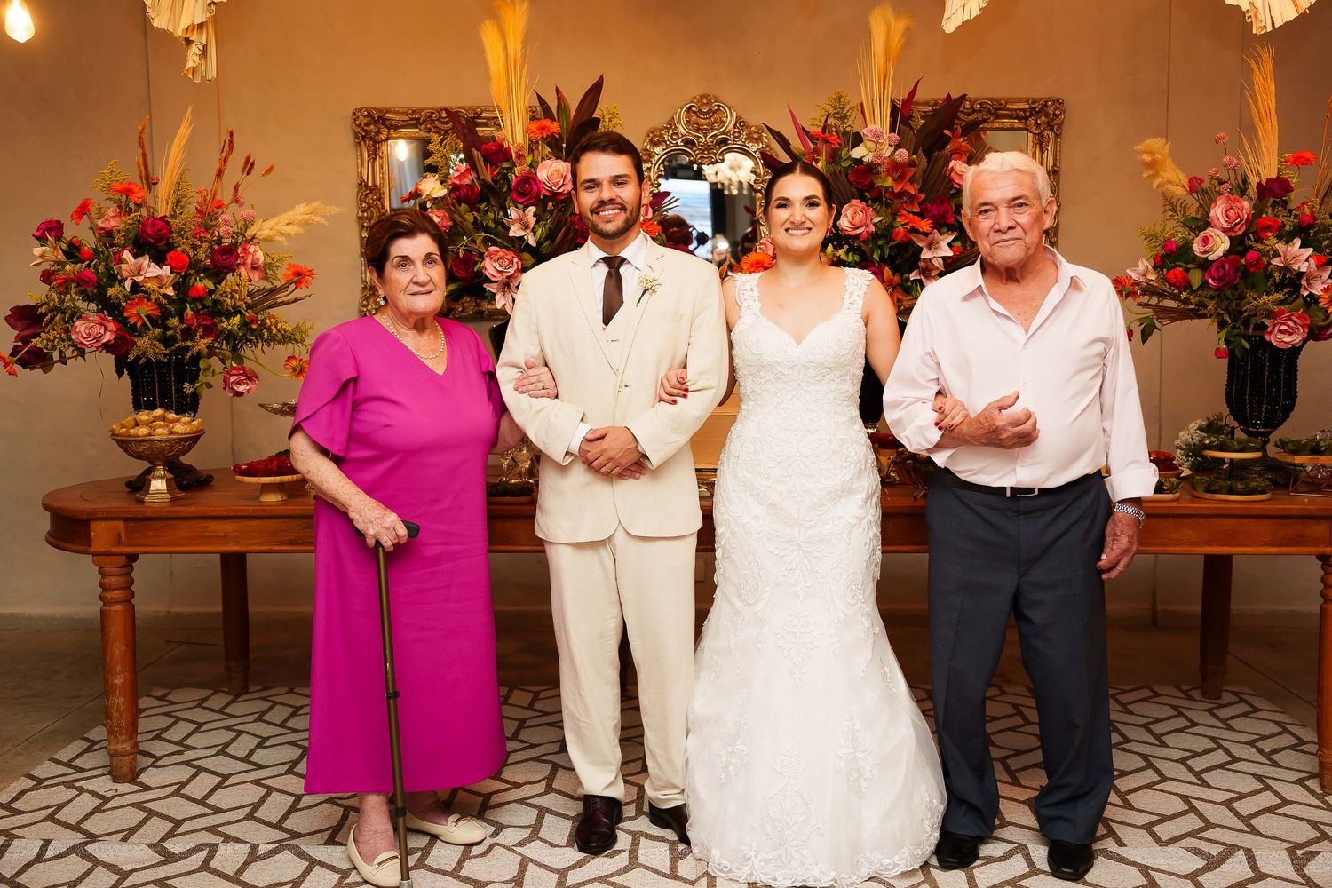 Bride and groom pose with family members at elegant wedding reception with colorful floral arrangements.