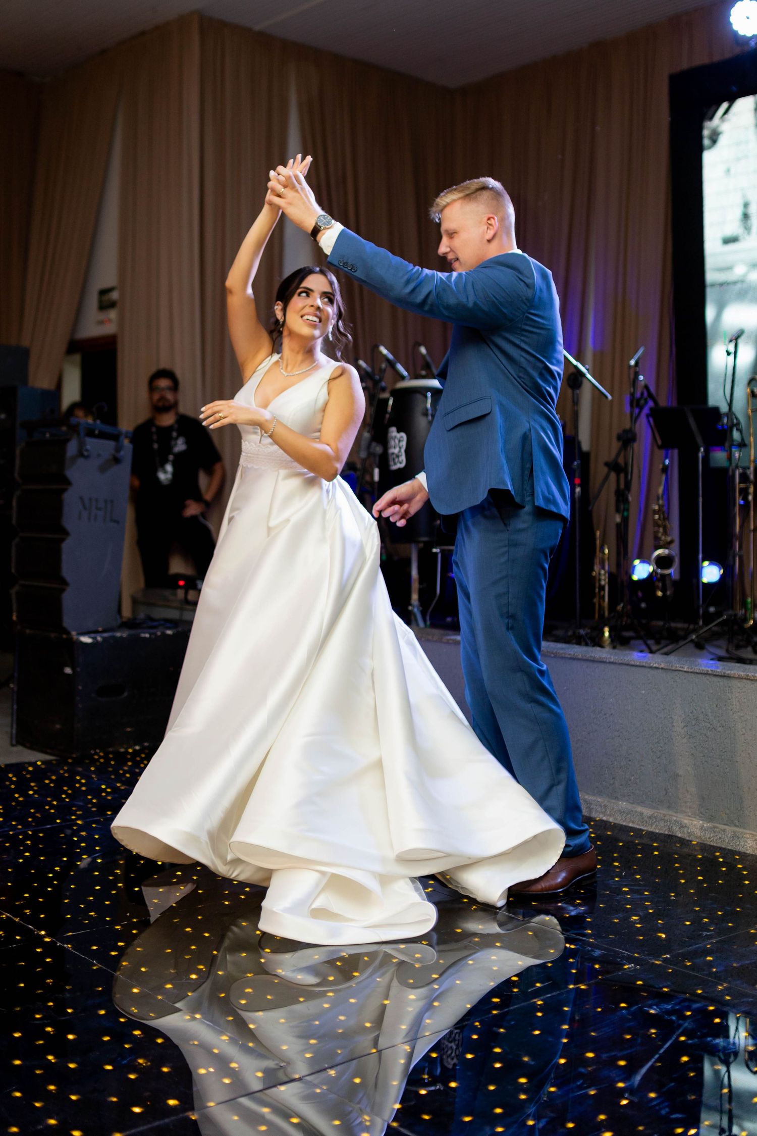 Bride and groom share their first dance, with groom spinning bride in white gown on starlit ballroom floor.