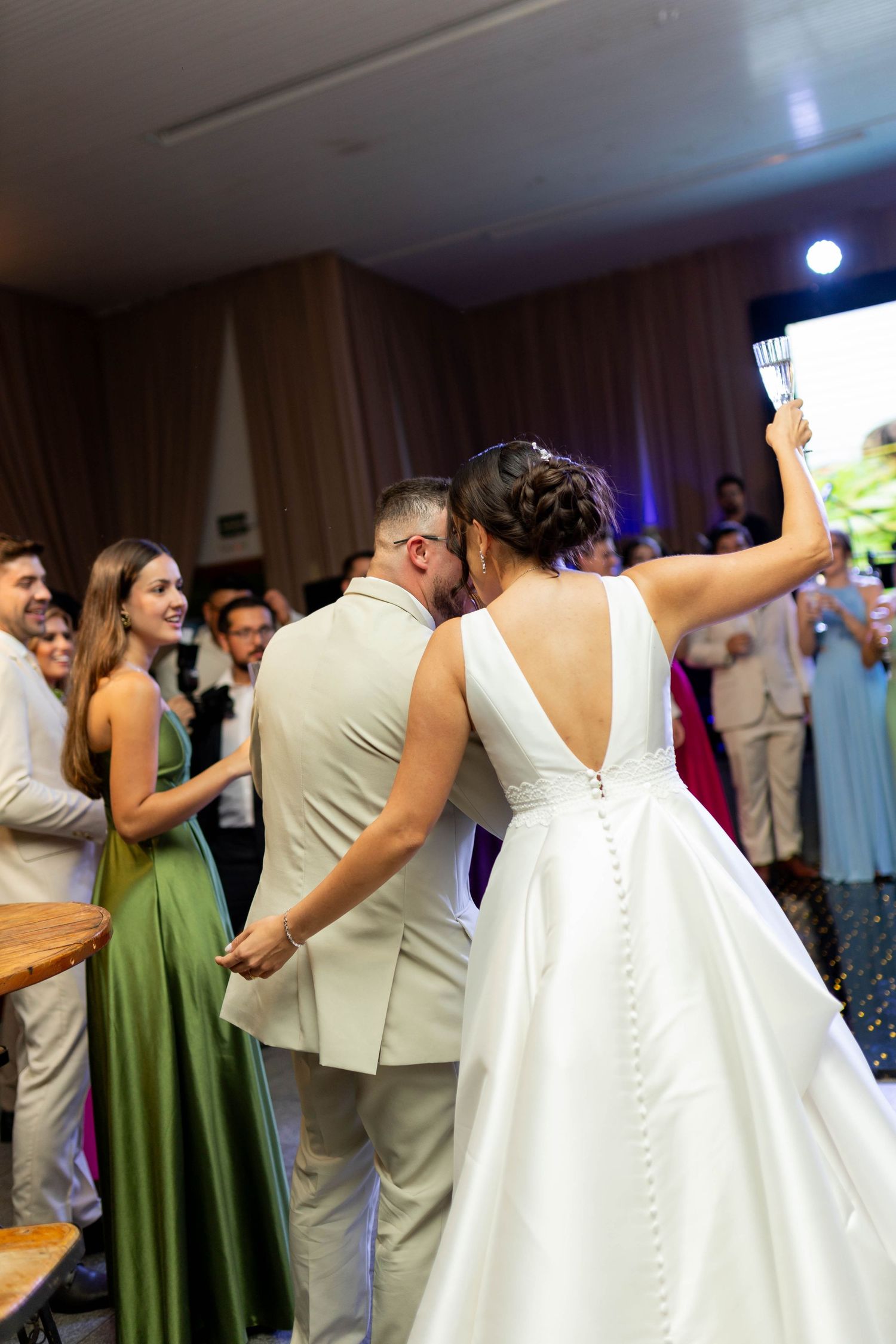 Bride and groom share a kiss during their wedding reception while guests celebrate around them.