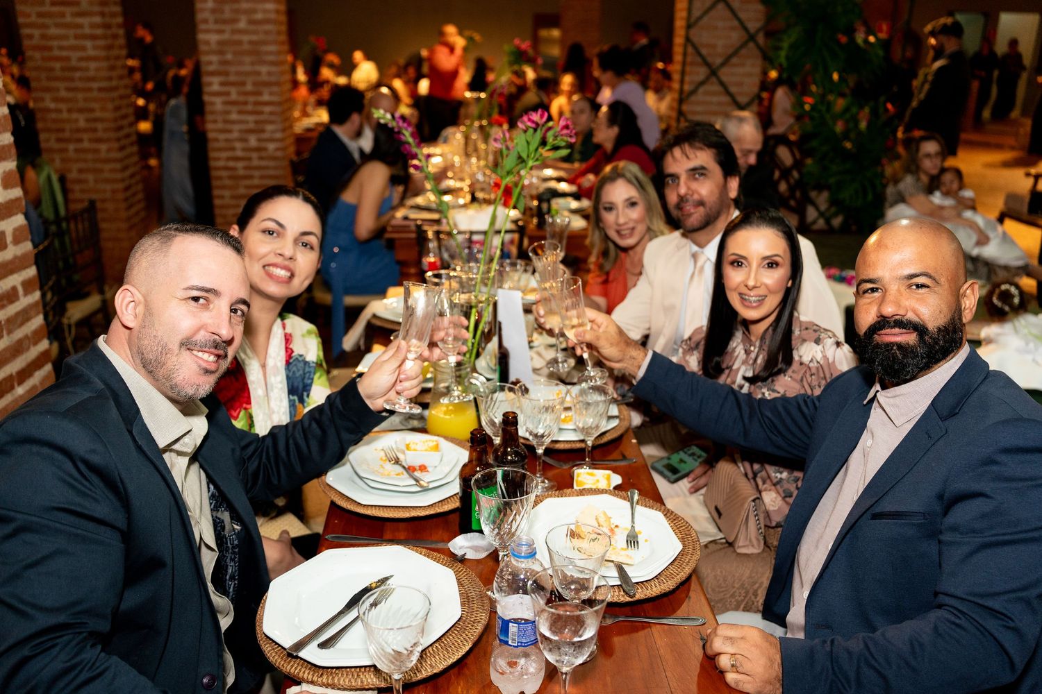 Six friends toast with wine glasses at a festive dinner table in an elegant restaurant setting.