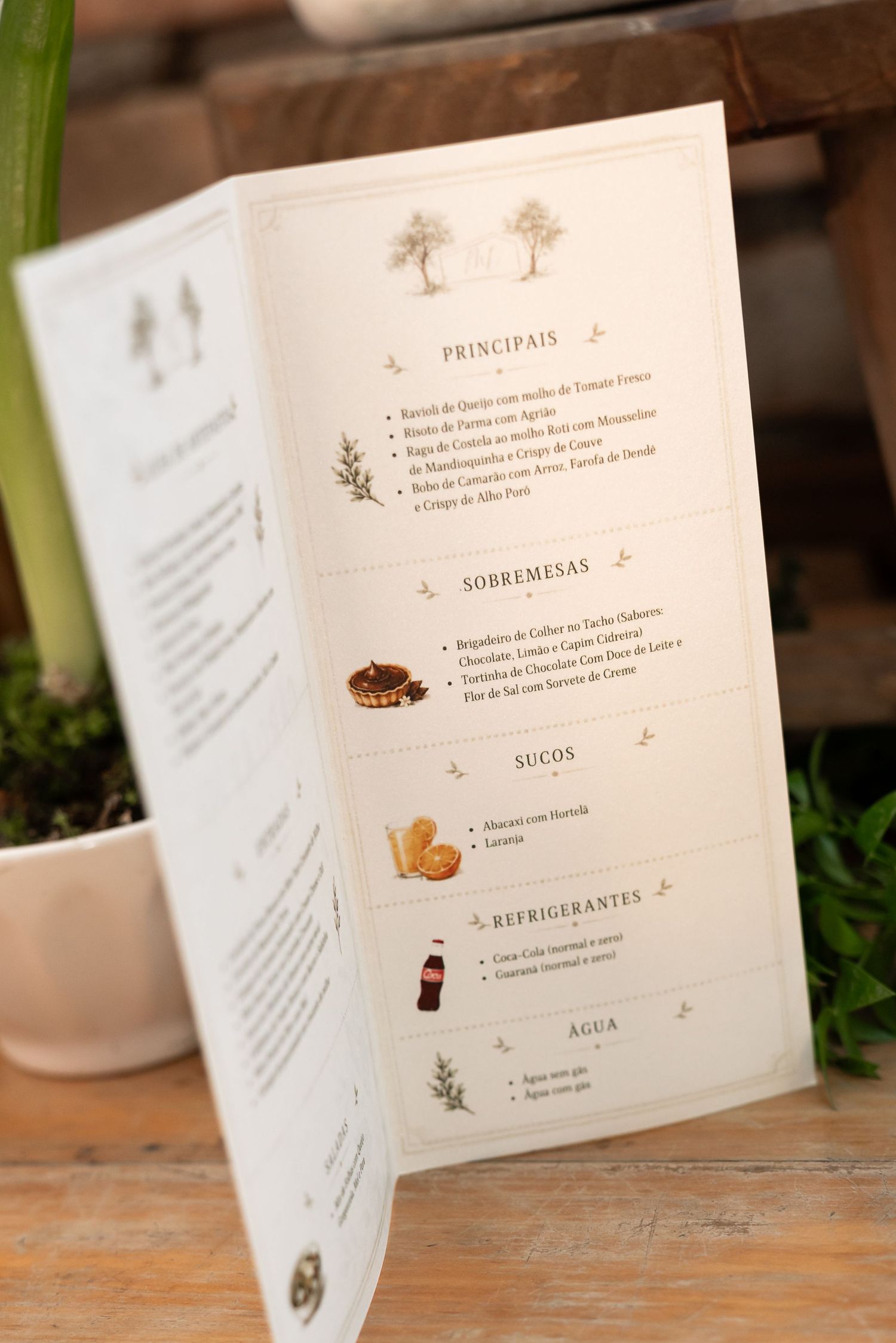 A folded restaurant menu in Portuguese displayed on a wooden table, featuring sections for mains, desserts, juices, and drinks.