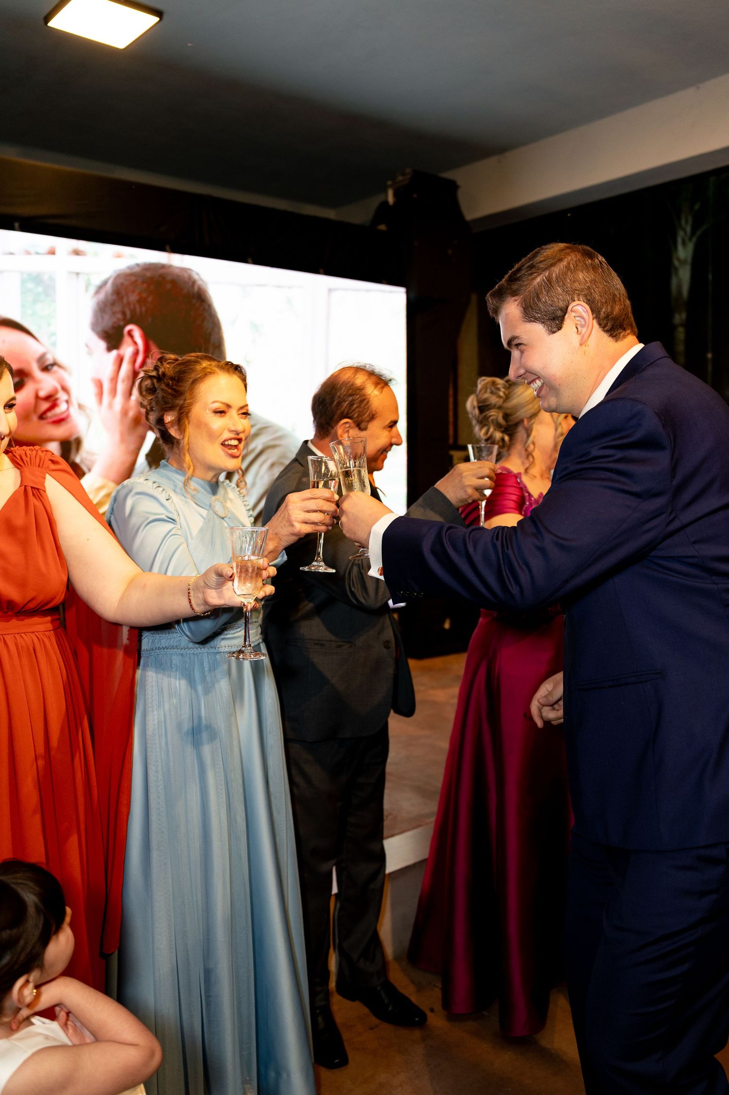 Elegantly dressed guests toasting with champagne glasses at a formal wedding reception party.