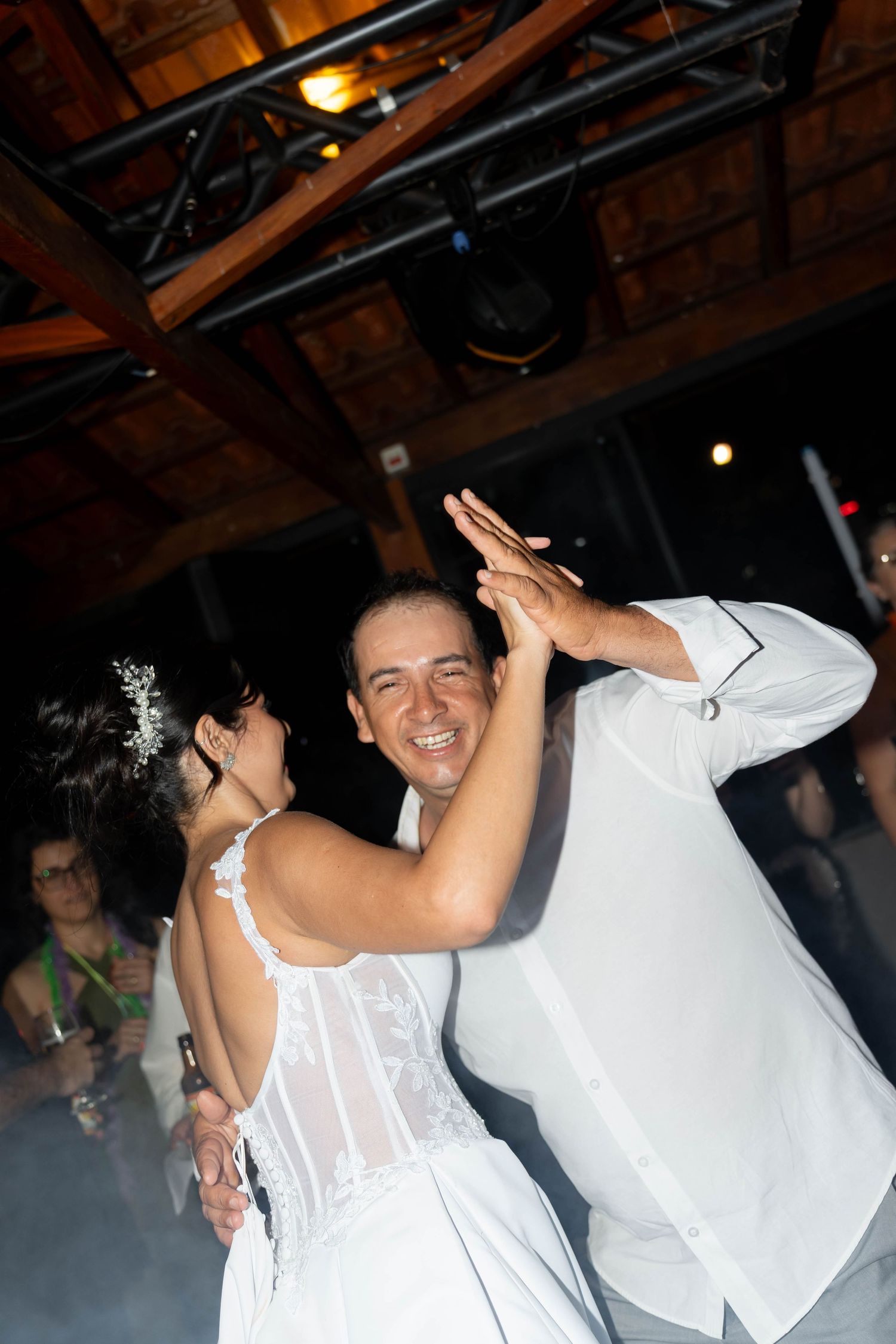Bride and groom sharing their first dance at a wedding reception, smiling joyfully under stage lights.