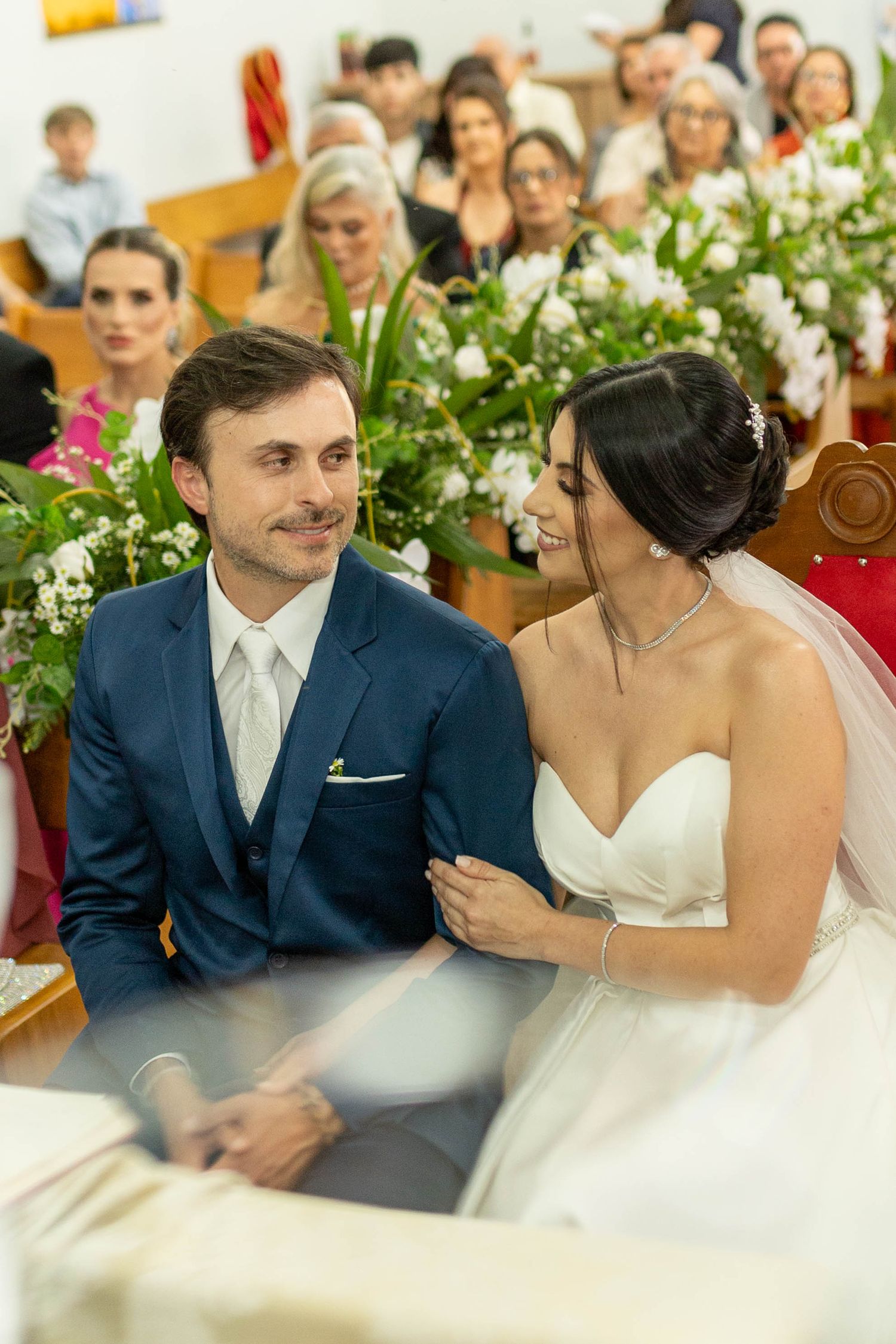 Bride and groom share a joyful moment at church altar during wedding ceremony with guests seated in pews behind them.