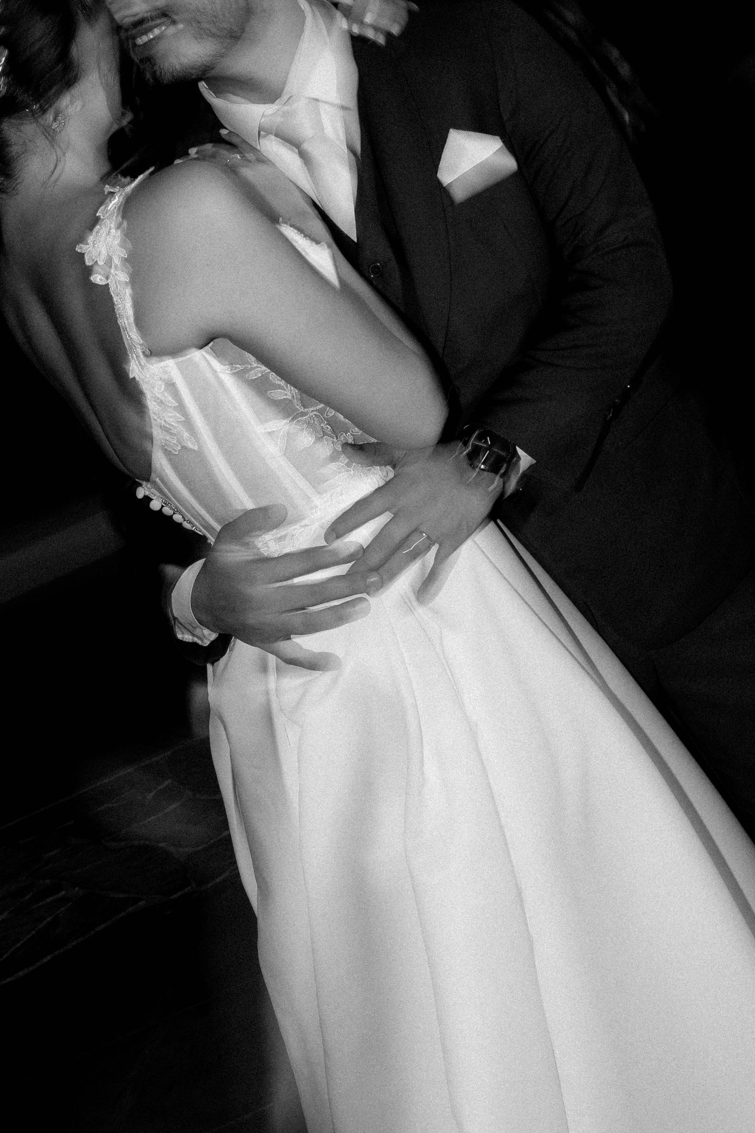 Black and white photo of a bride and groom sharing an intimate dance, the groom's hands wrapped around her waist.