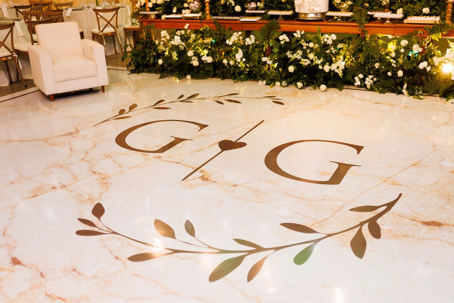 Elegant marble wedding dance floor with gold monogram G&G initials and olive branch wreath design.