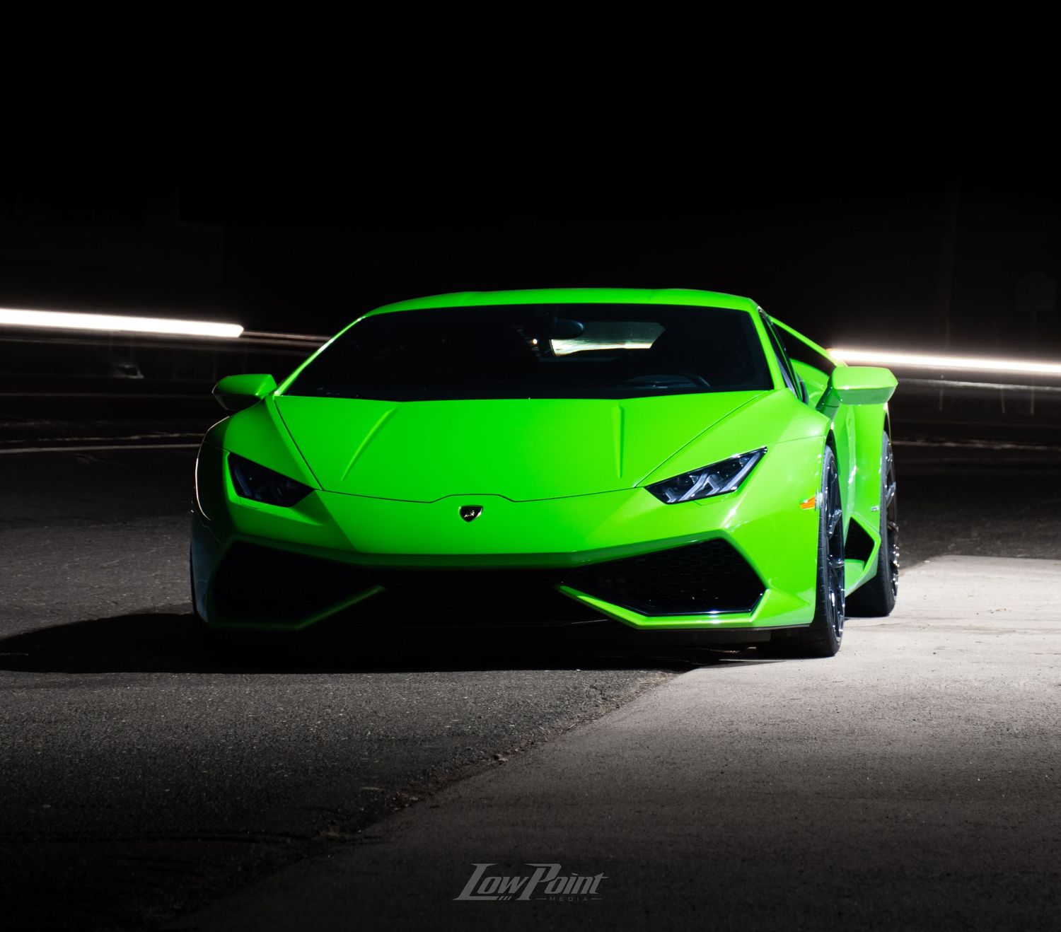 Green Lamborghini Huracan photographed with moody lighting and black background at night