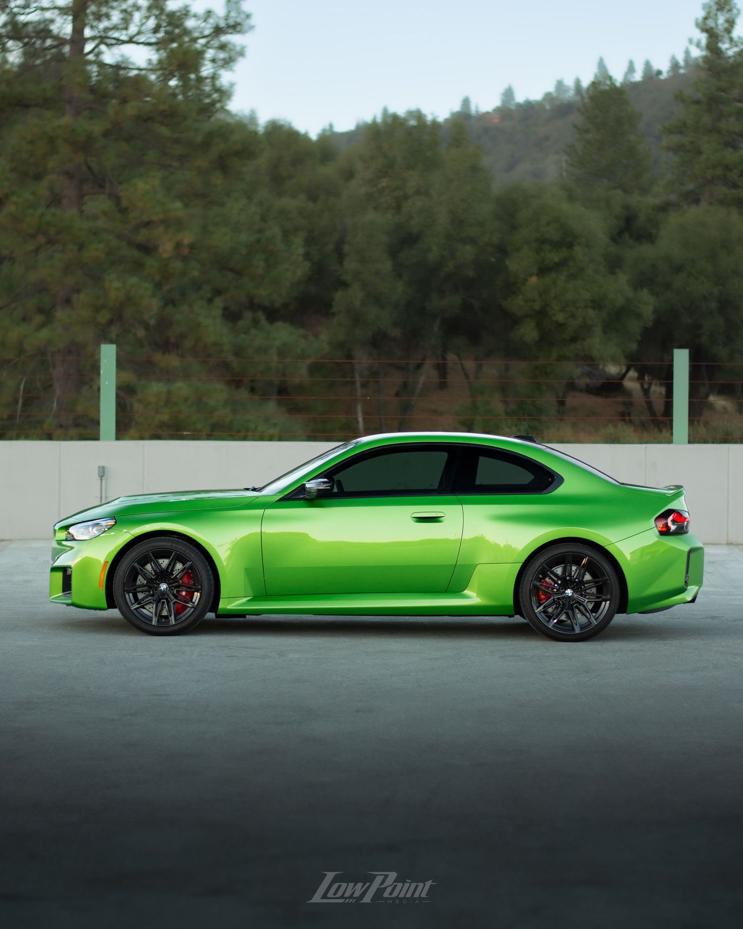 Java Green BMW photographed on the top of a parking garage during golden hour with moody clouds and trees in the background