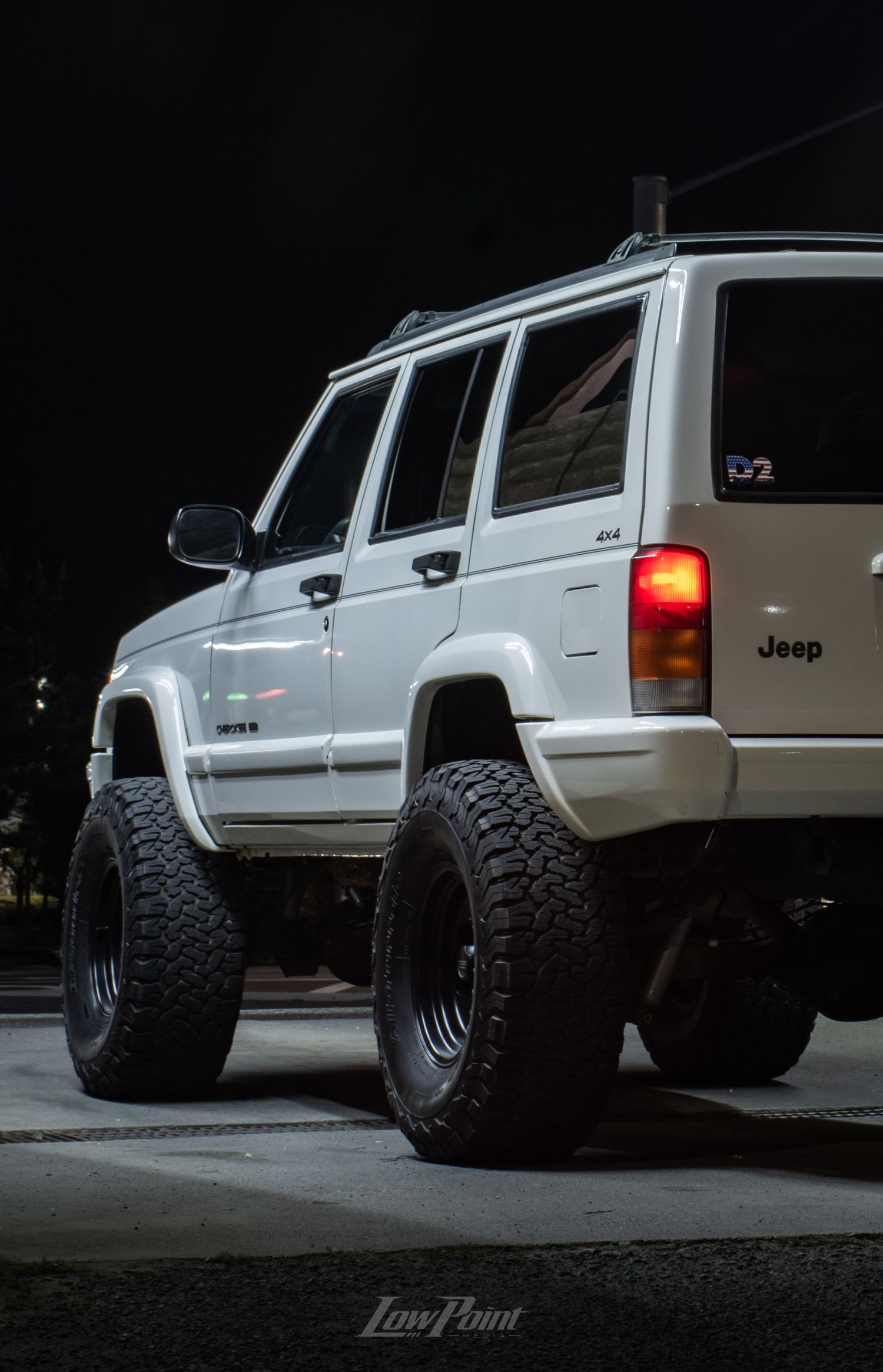 White Jeep Cherokee photographed at night inside a self-service car wash with moody lighting at night