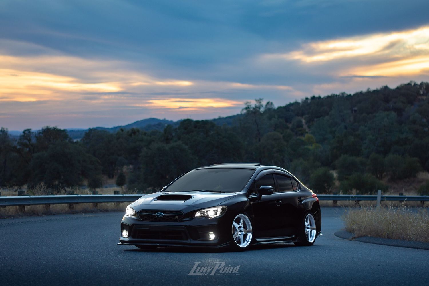 Black Subaru WRX photographed on the side of a northern California road with a blue and orange sunset behind