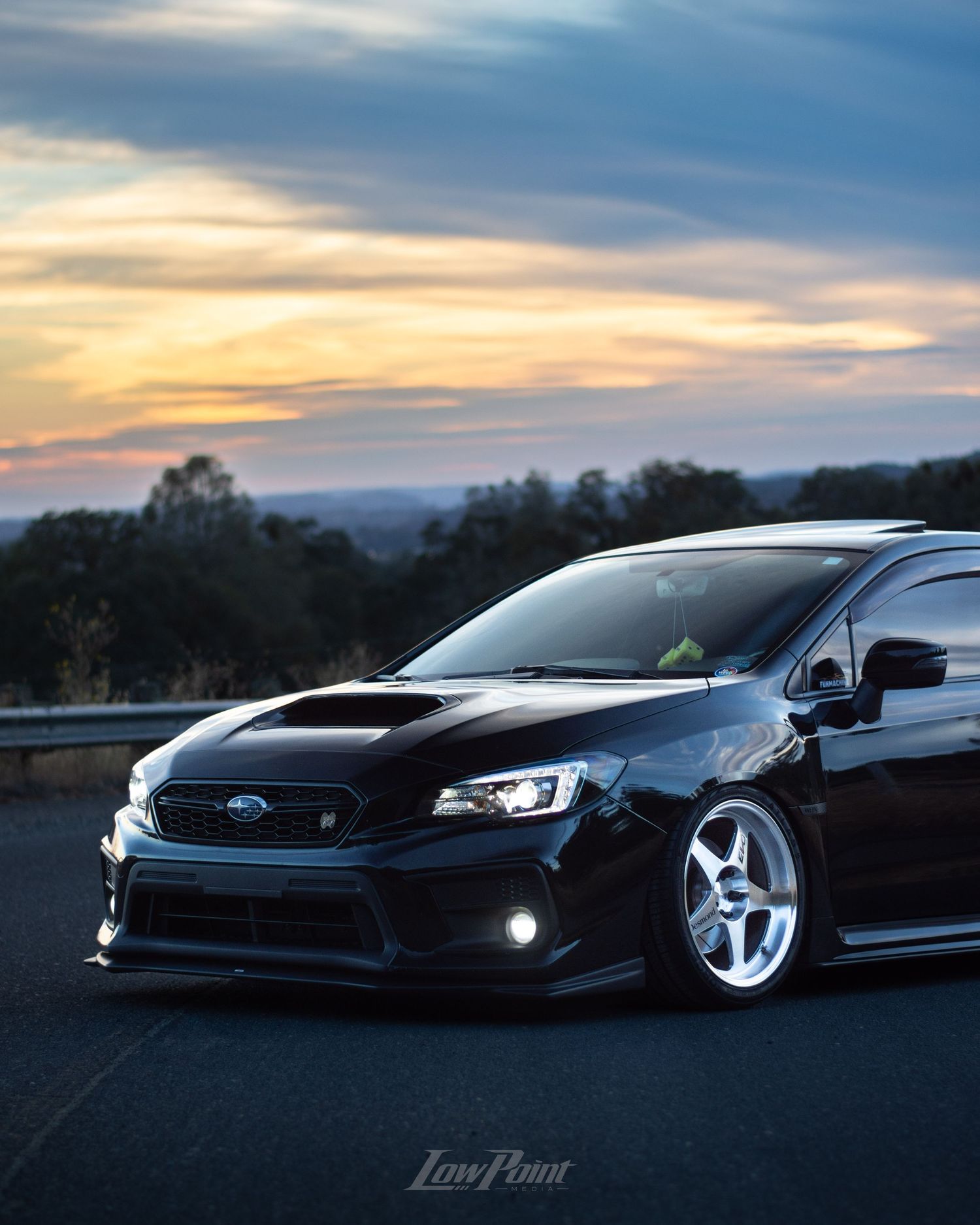 Black Subaru WRX photographed on the side of a northern California road with a blue and orange sunset behind