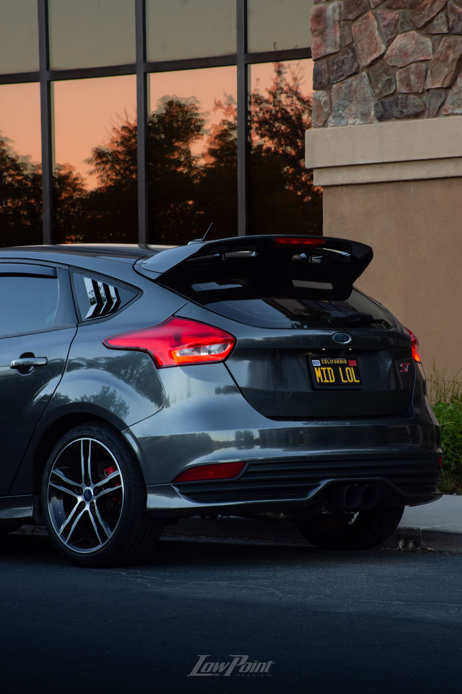 Magnetic Grey Ford Focus ST photographed in front of building with large modern windows reflecting a colorful sunset