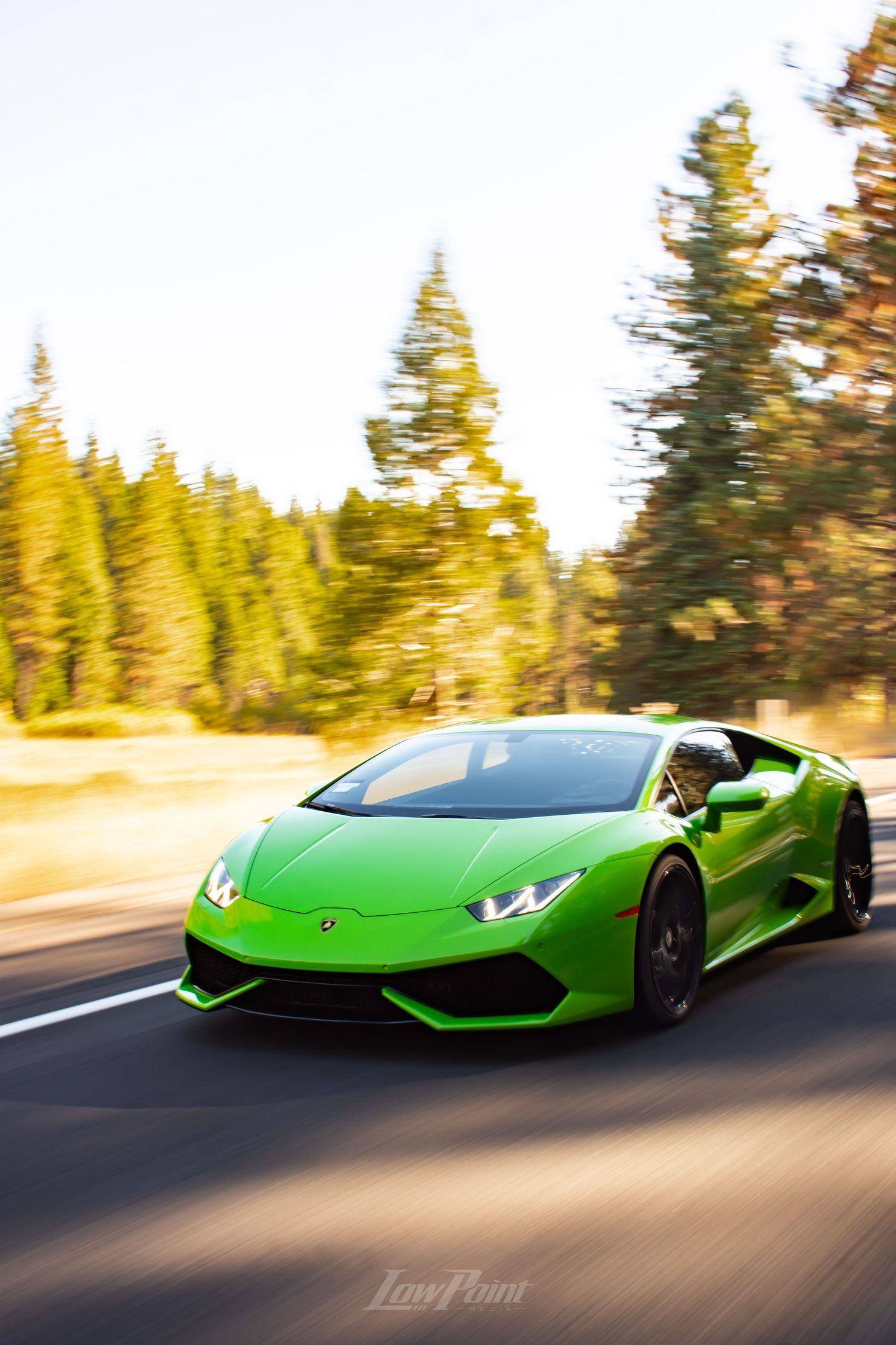 Green Lamborghini Huracan photographed rolling in motion with golden sunset mountains in the background