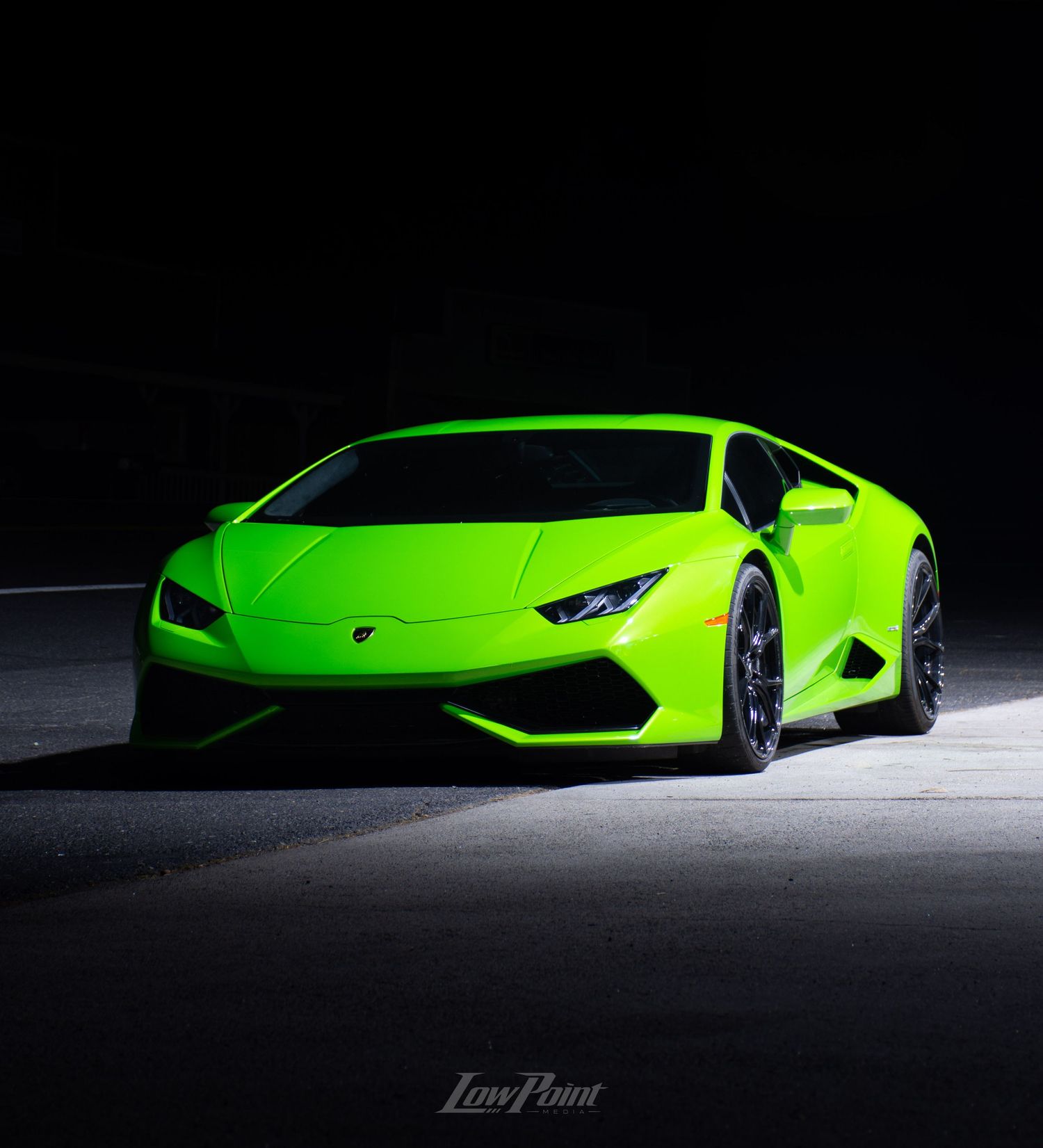 Green Lamborghini Huracan photographed with moody lighting and black background at night