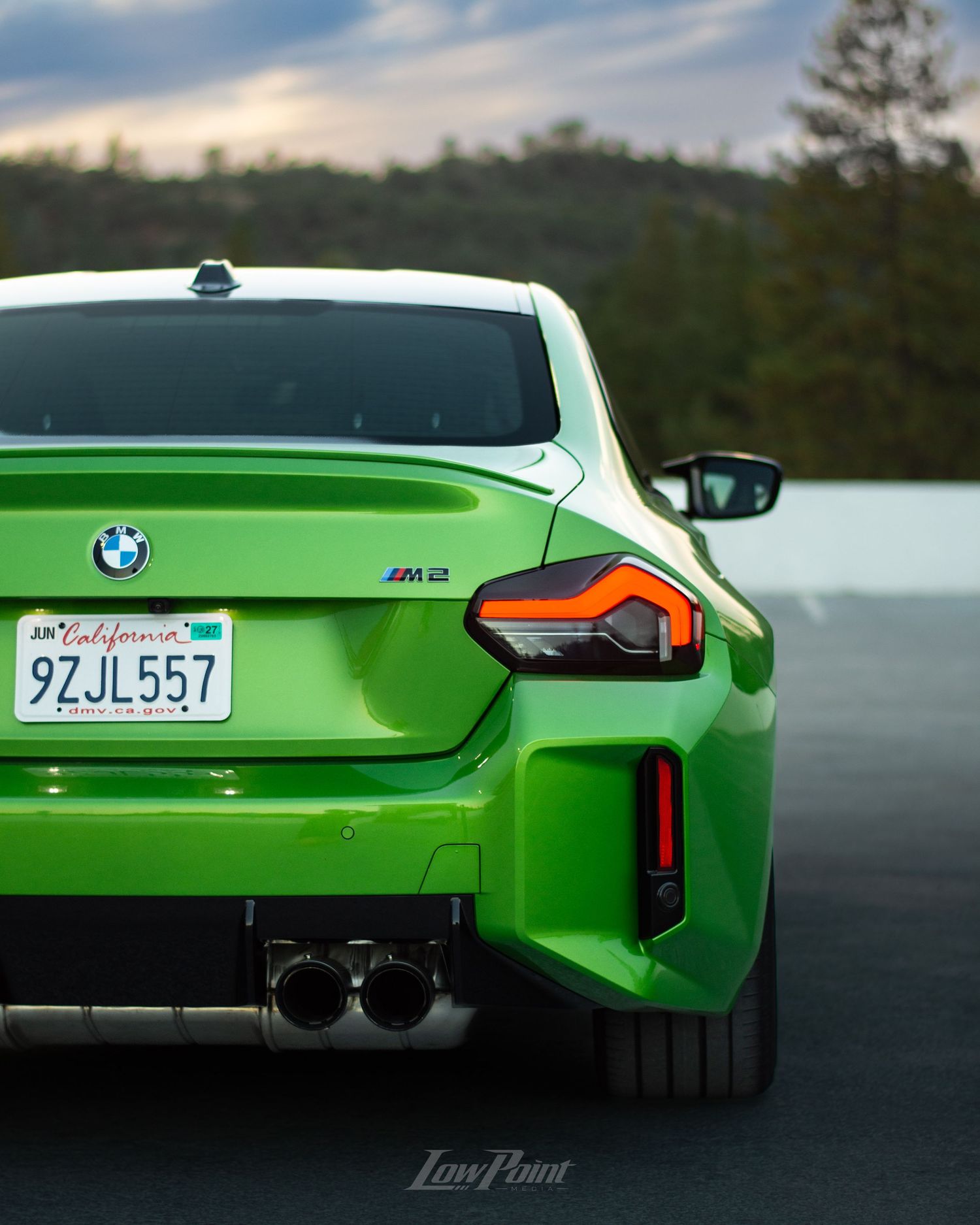 Java Green BMW photographed on the top of a parking garage during golden hour with moody clouds and trees in the background