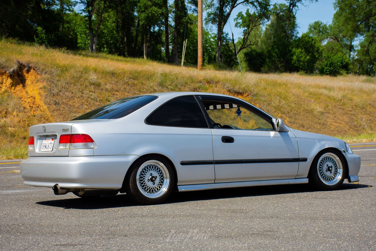 Silver Honda Civic photographed on northern California roadside with golden hill in background