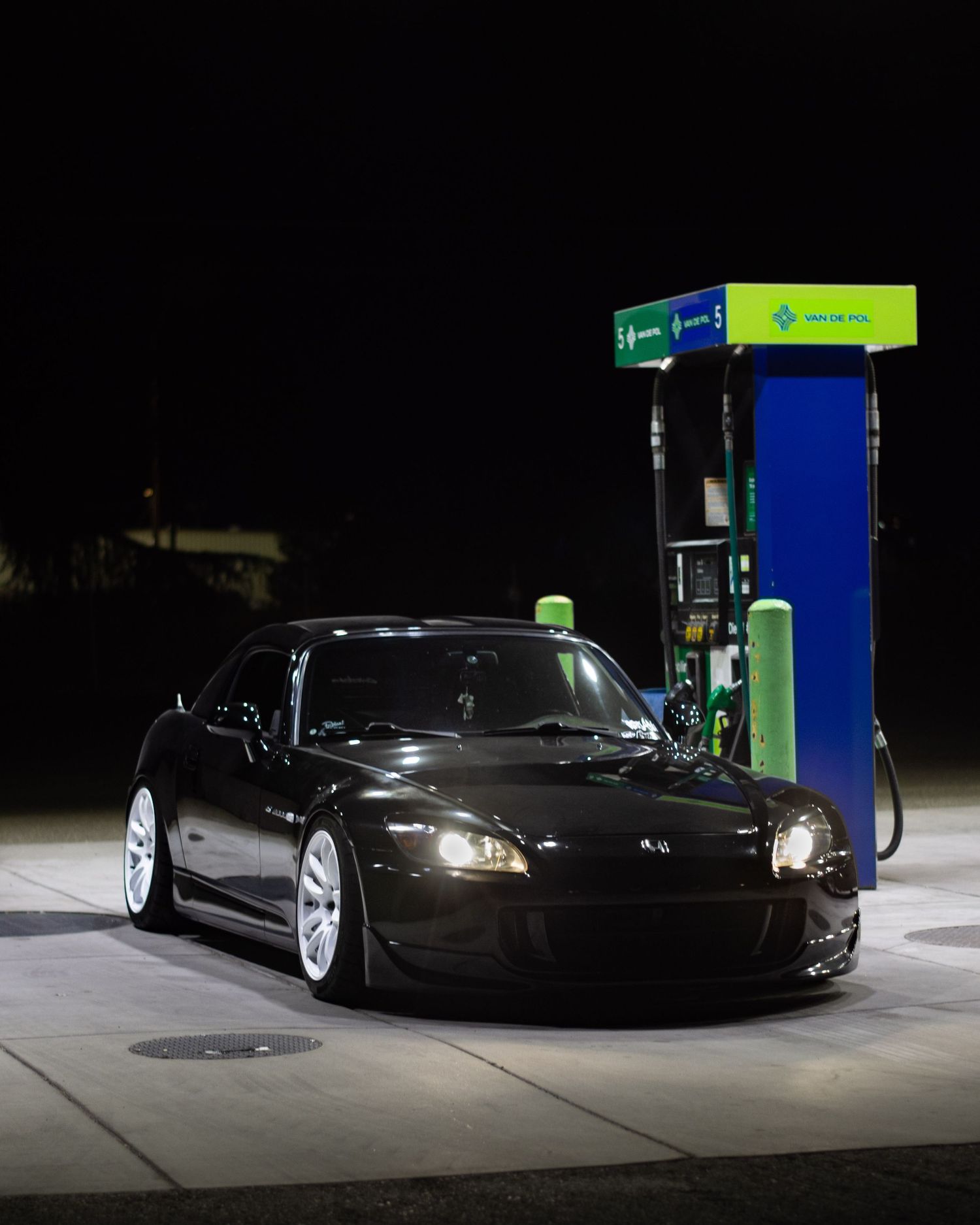 Black Honda S2000 photographed at night at a gas pump with white Work wheels