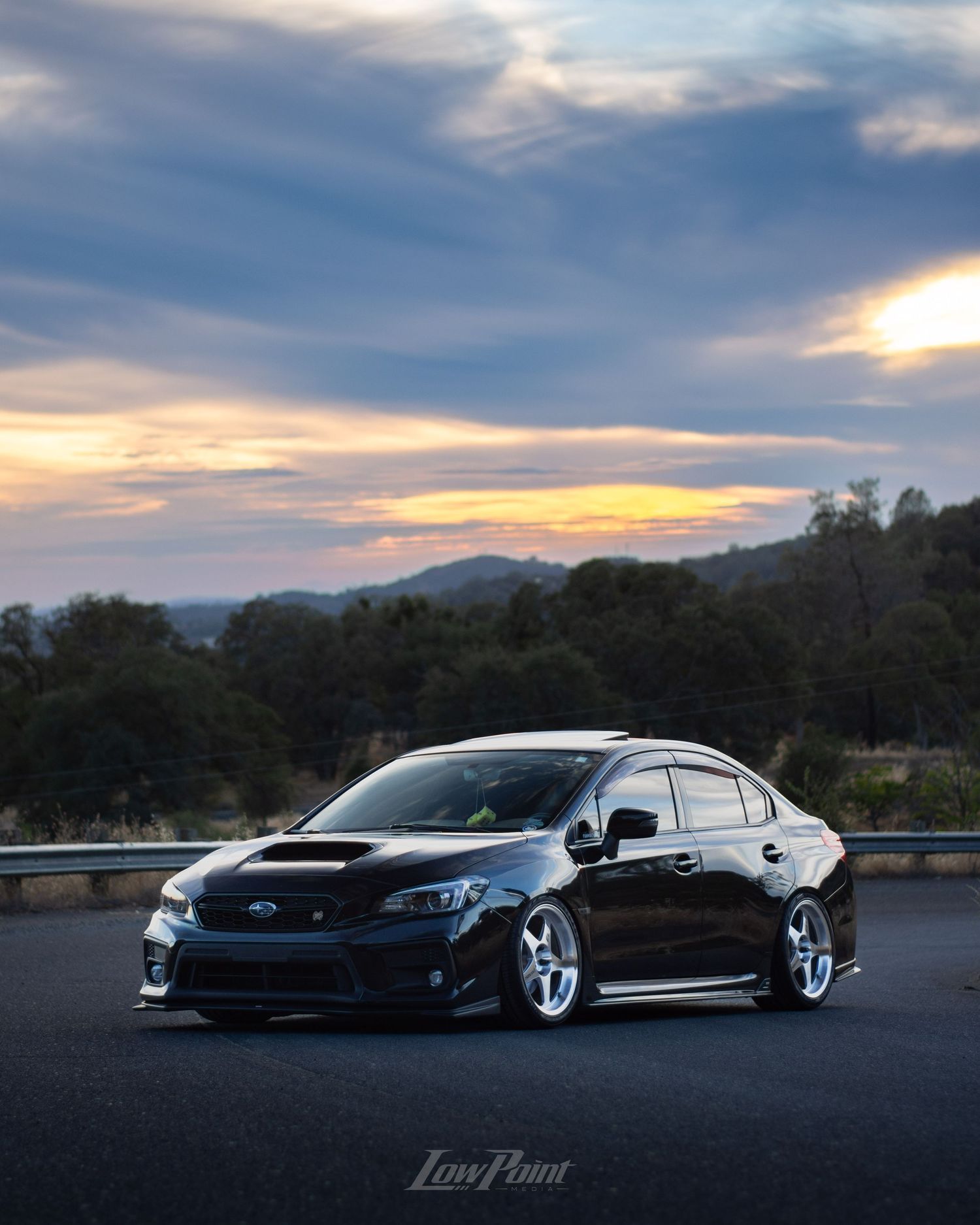 Black Subaru WRX photographed on the side of a northern California road with a blue and orange sunset behind