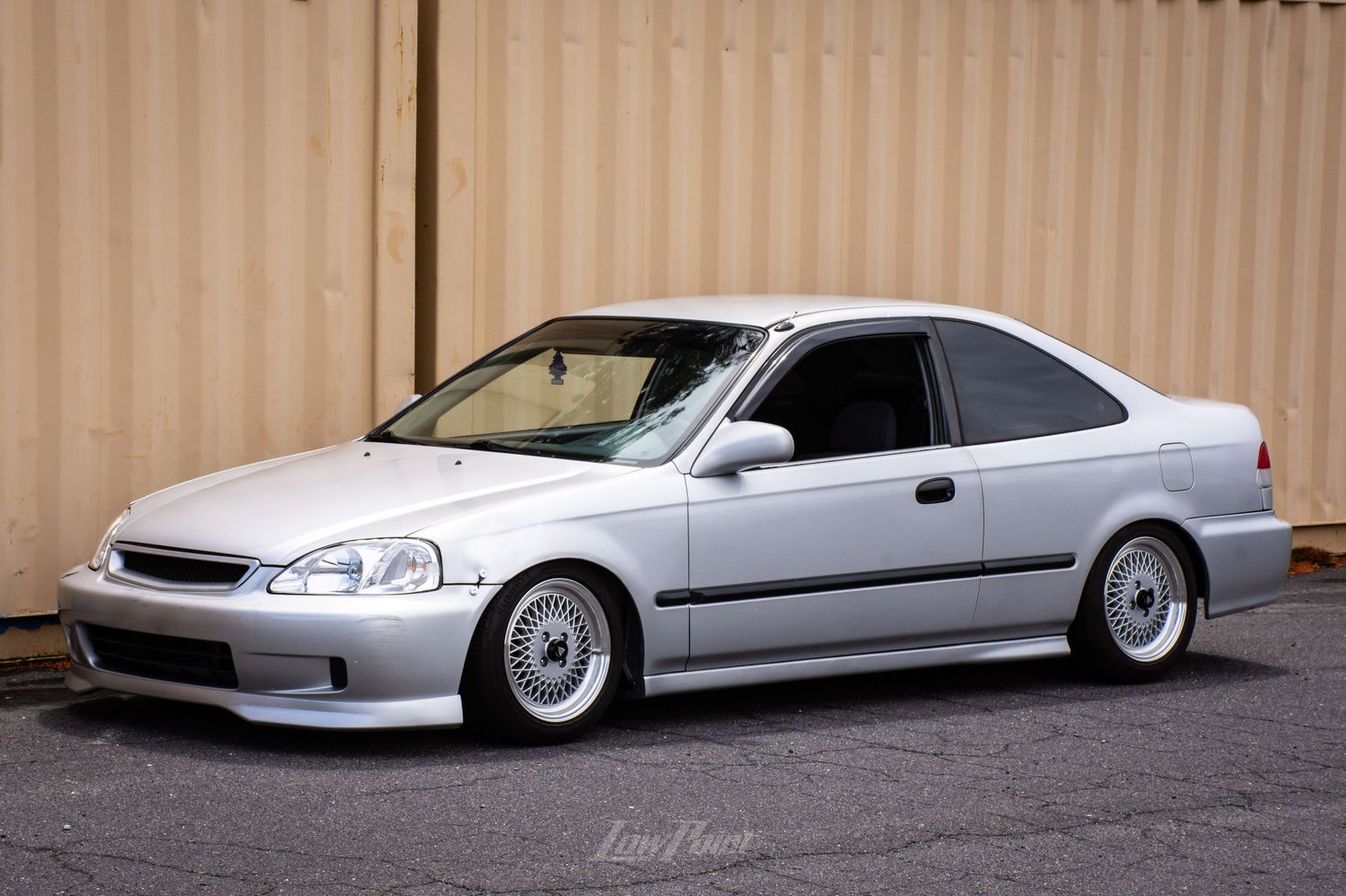 Silver Honda Civic photographed in front of an industrial shipping container