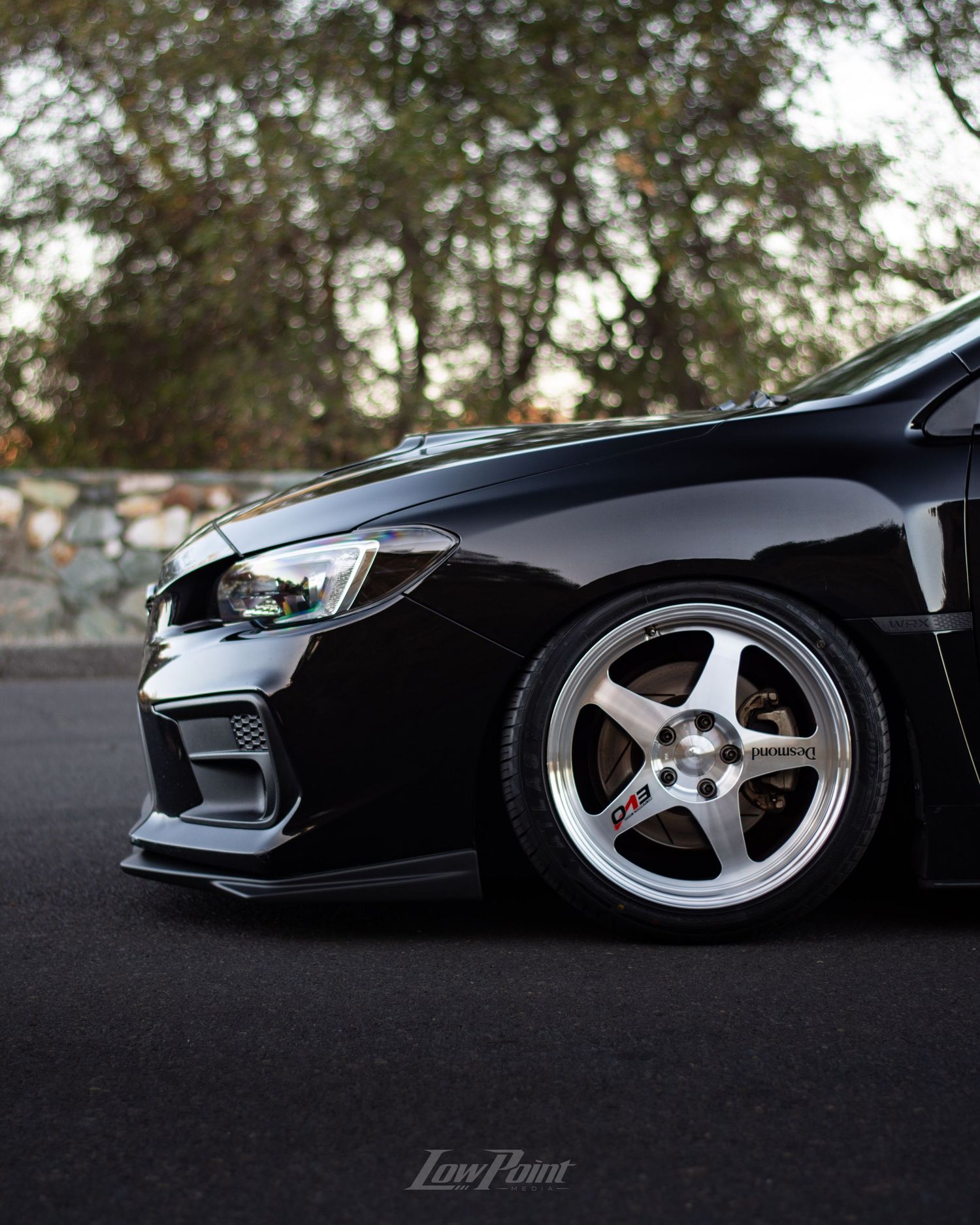 Black Subaru WRX photographed at a vista point overlooking a lake with a bridge