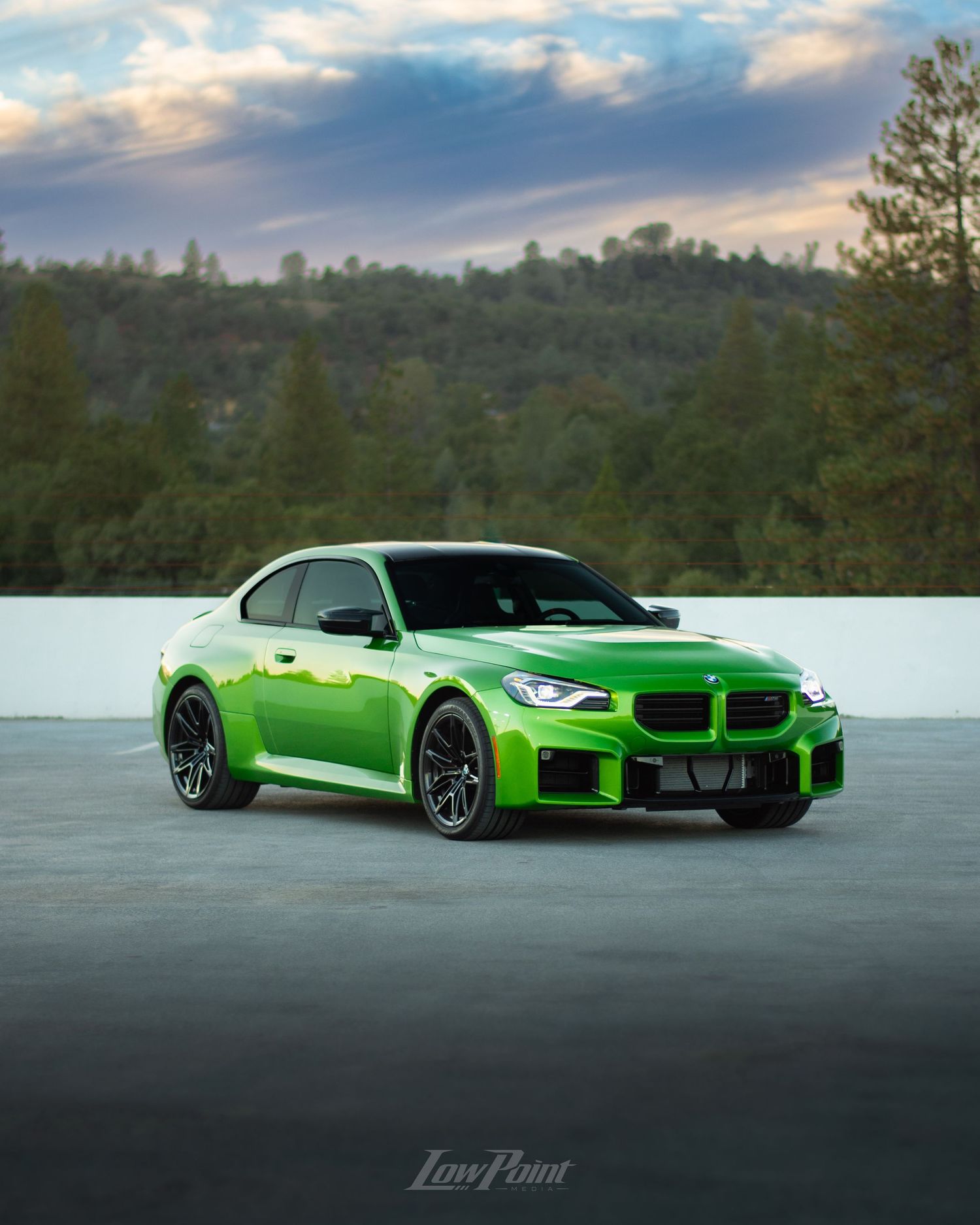 Java Green BMW photographed on the top of a parking garage during golden hour with moody clouds and trees in the background