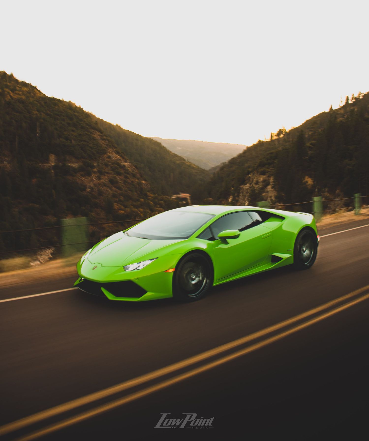 Green Lamborghini Huracan photographed rolling in motion with golden sunset mountains in the background