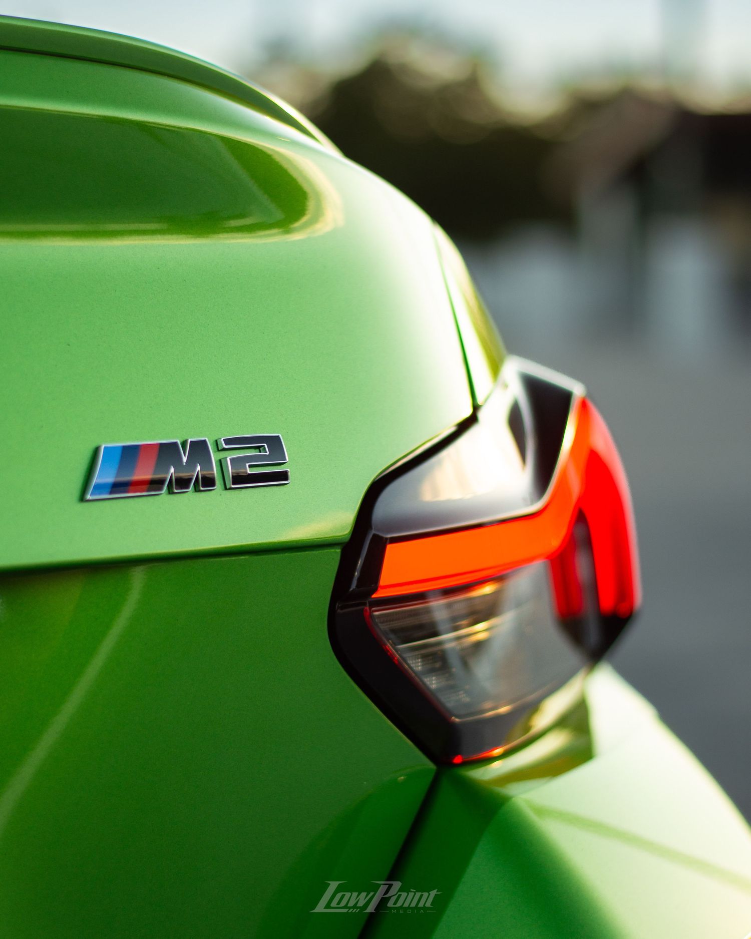 Java Green BMW photographed on the top of a parking garage during golden hour with moody clouds and trees in the background
